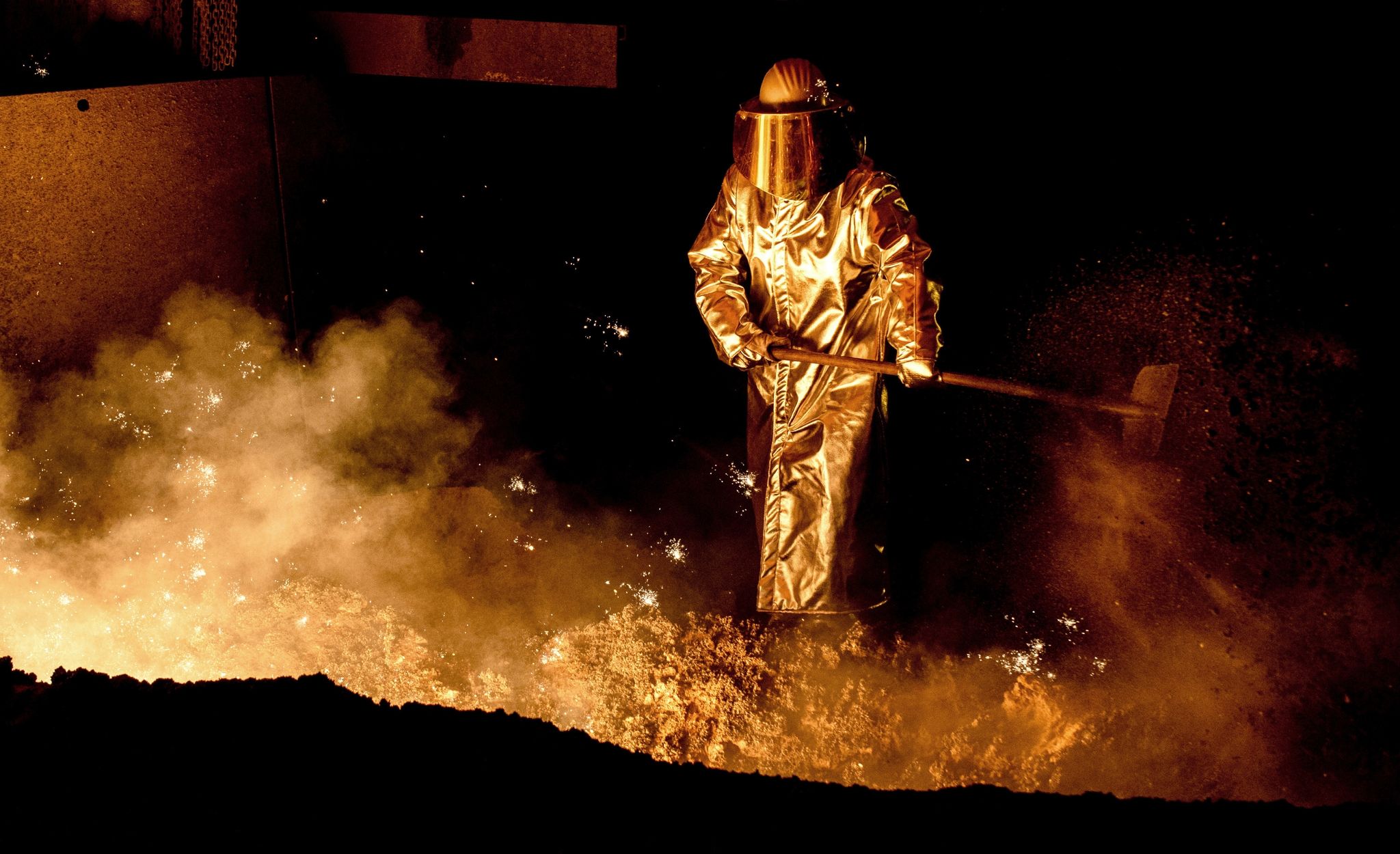 Ein Mitarbeiter schaufelt in einem Stahlwerk Sand in die Abstichrinne am Hochofen. Die Bundesregierung kann der deutschen  Stahlindustrie beim Umbruchin eine klimafreundlichere Zukunft helfen.