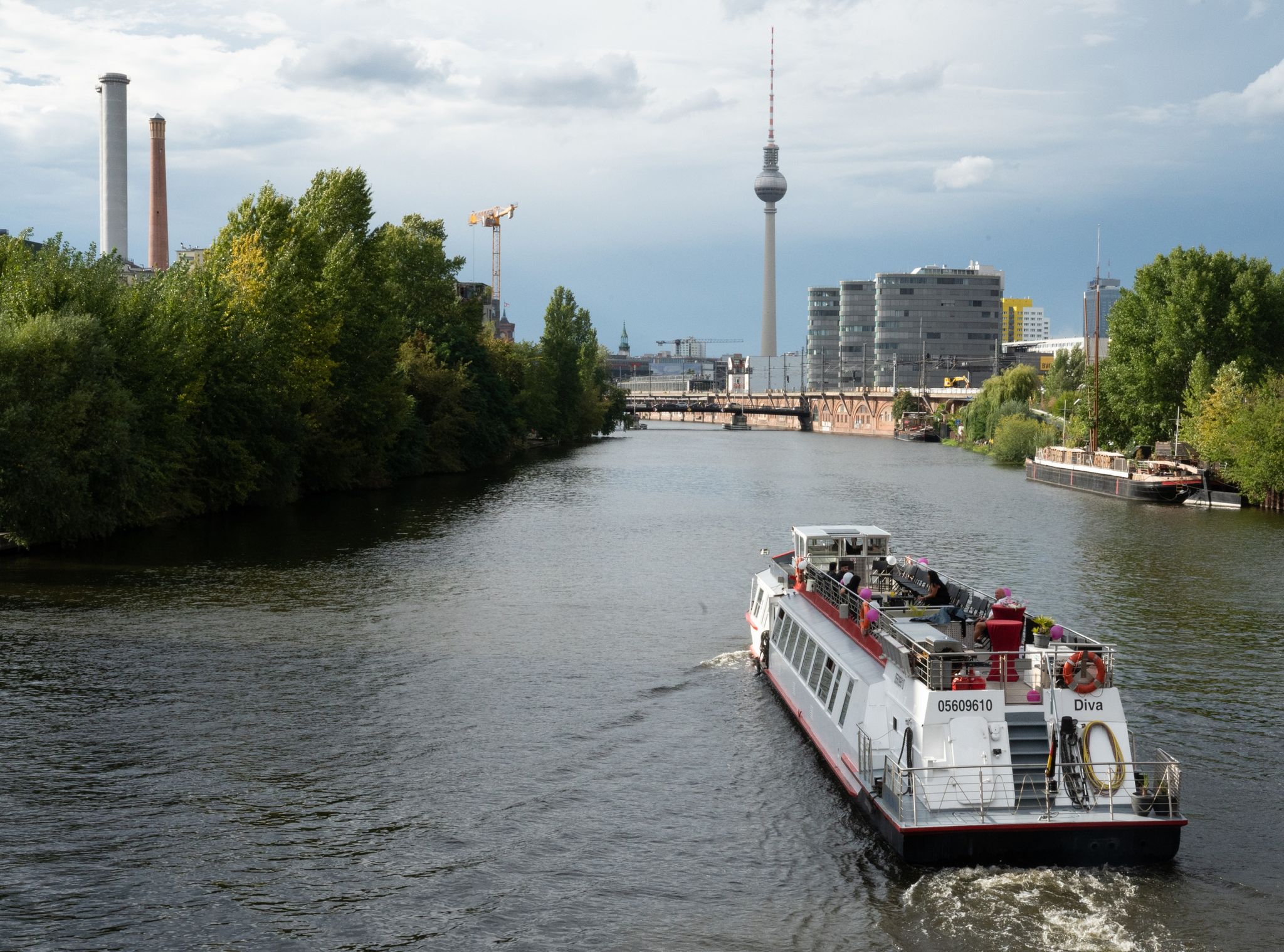 Ein Ausflugsschiff fährt in der Nähe der East Side Gallery in Berlin über die Spree.