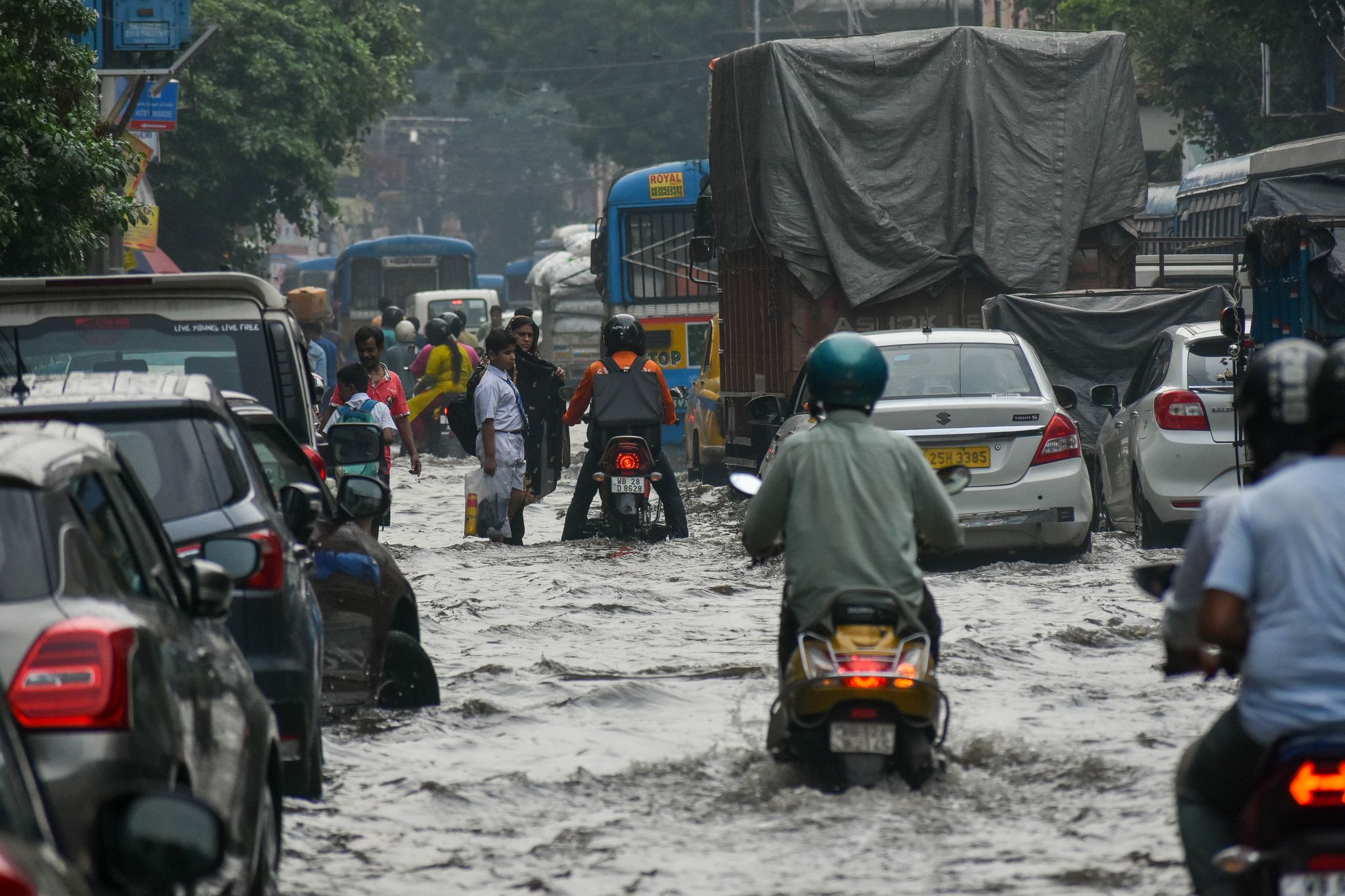 Menschen bahnen sich nach heftigen Regenfällen den Weg über eine überflutete Straße in Kalkutta.