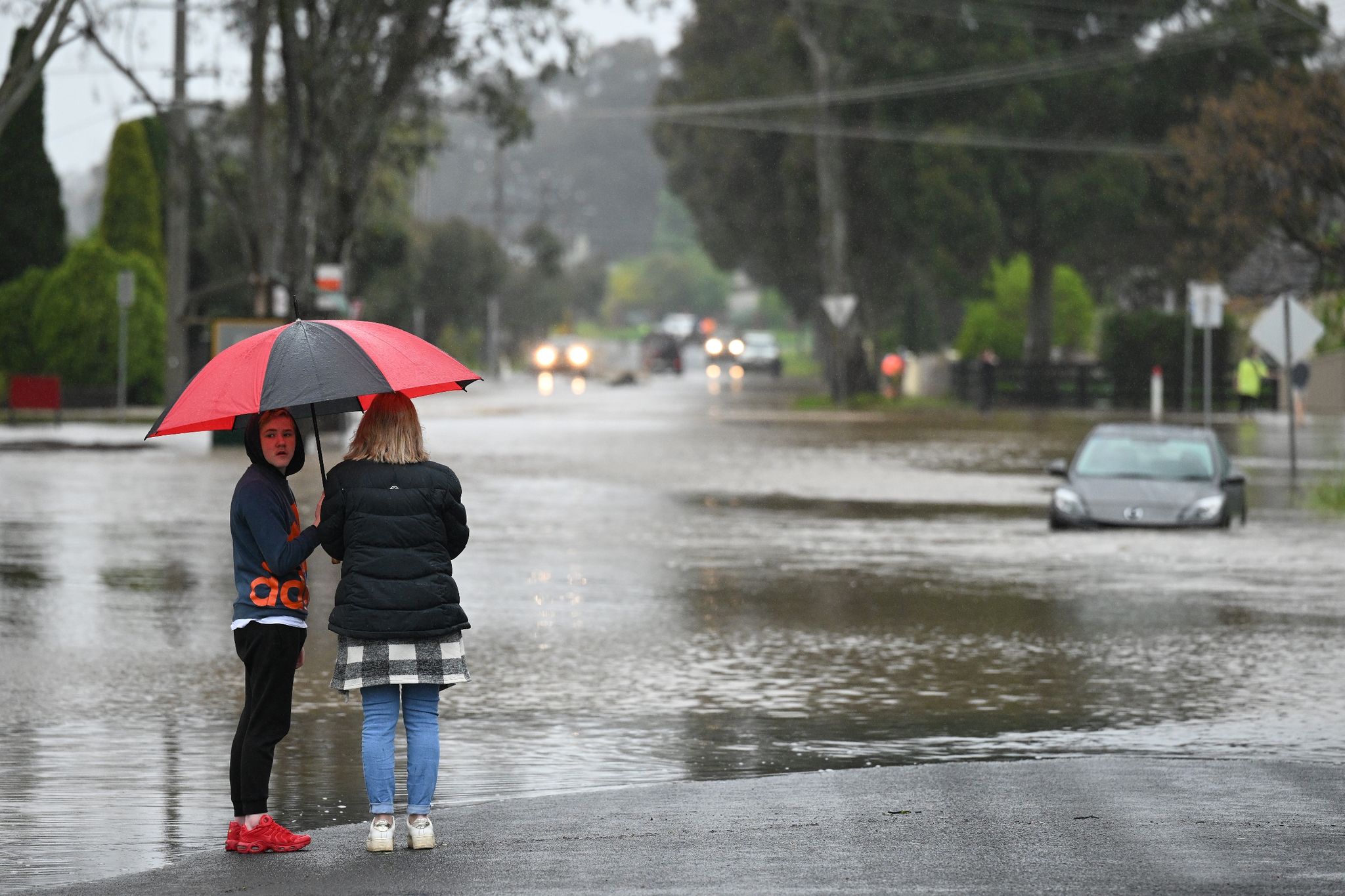 Menschen stehen an einer überschwemmten Straße in Melbourne.
