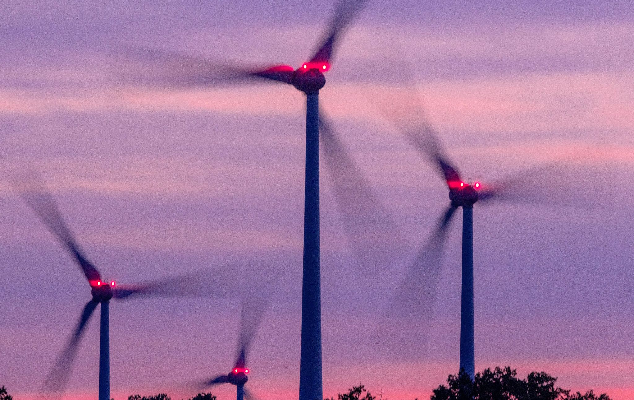 Windräder drehen sich nach Sonnenuntergang in einem mecklenburgischen Windpark.