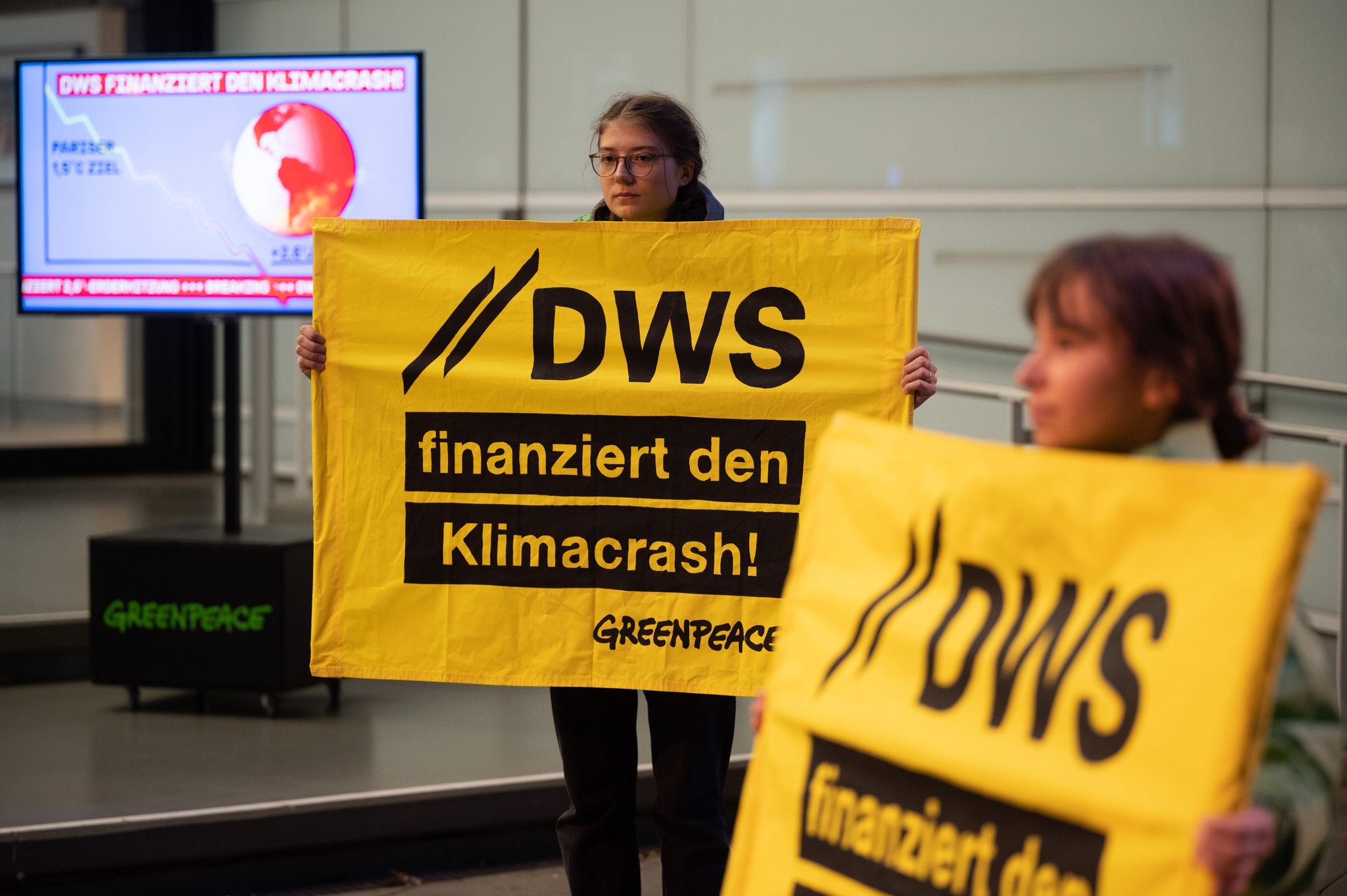 Demonstrierende halten vor dem Eingang des Vermögensverwalters DWS Schilder.