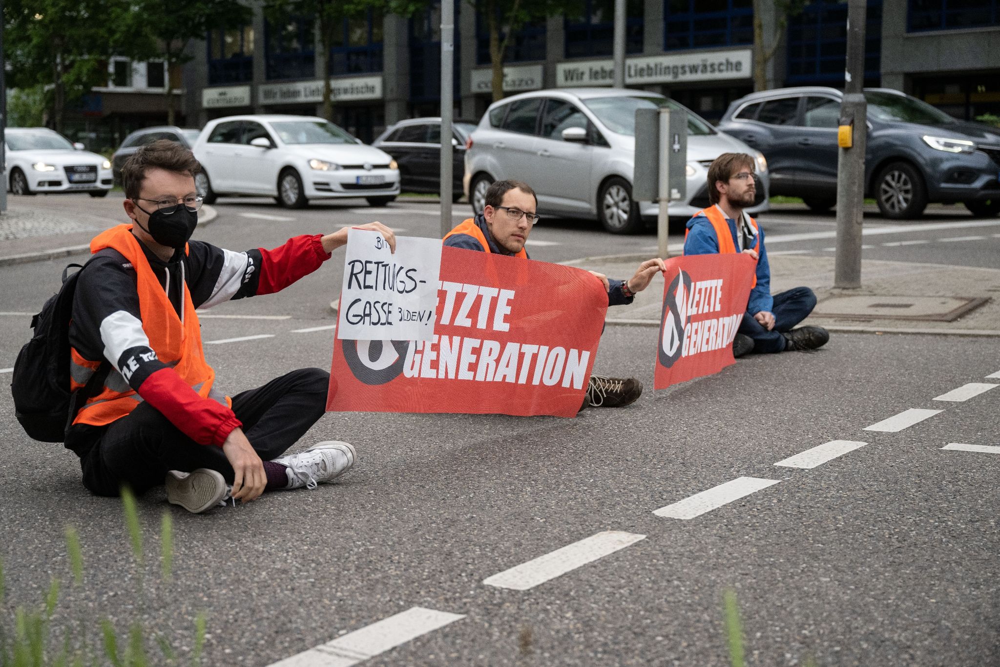 Drei Klimaaktivisten der Gruppe «Aufstand der letzten Generation» blockieren eine Straße in Stuttgart.