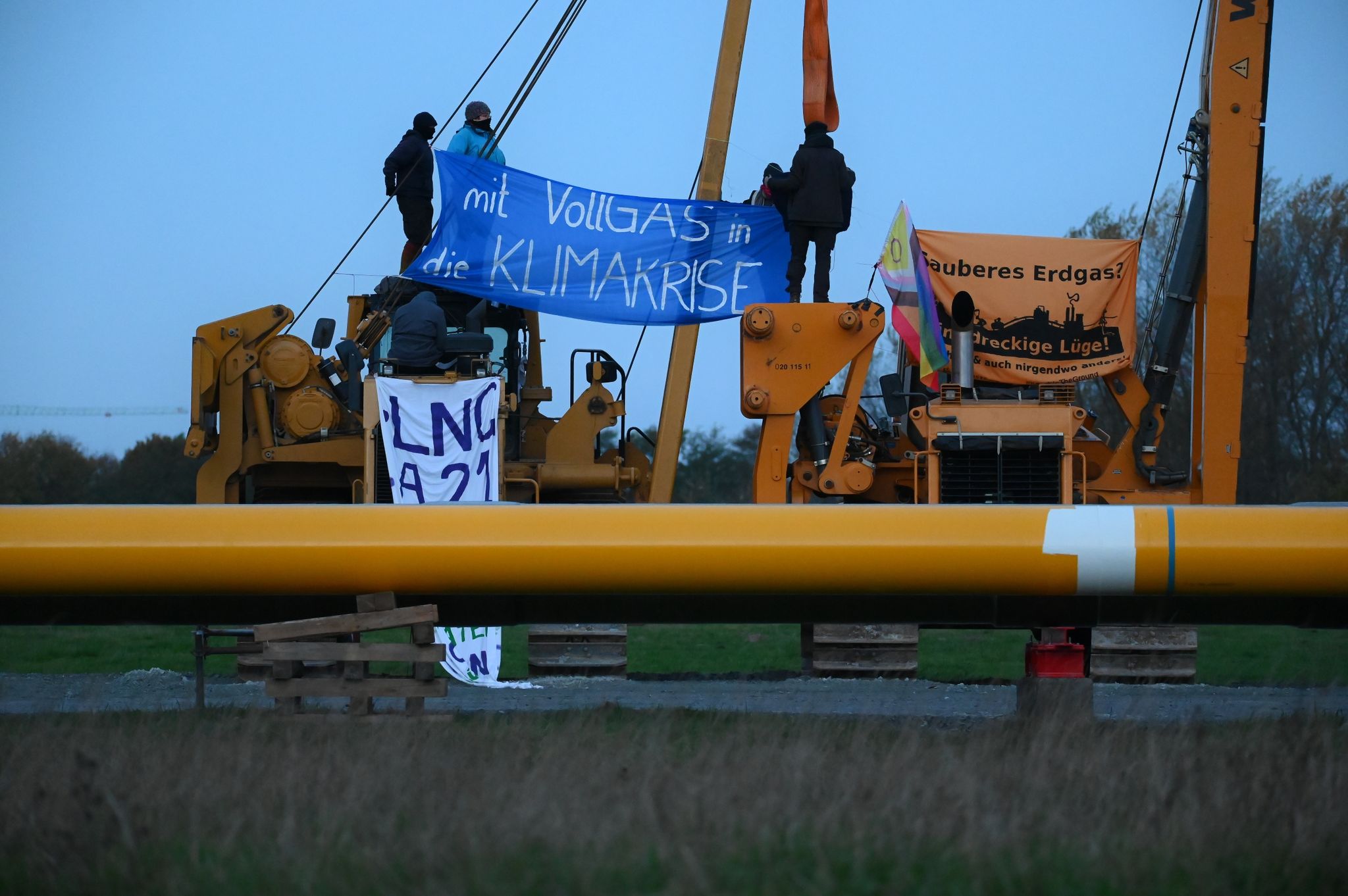Aktivisten sitzen auf Baufahrzeugen und haben Plakate mit der Aufschrift "mit Vollgas in die Klimakrise" und "Sauberes Erdgas? Eine dreckige Lüge" gespannt.
