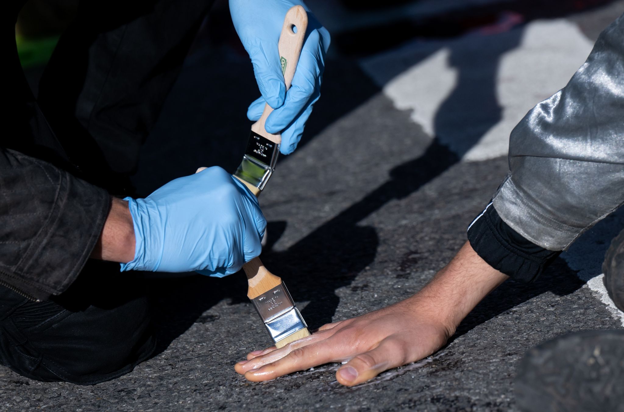 Ein Polizist löst die festgeklebte Hand eines Klimaaktivisten.