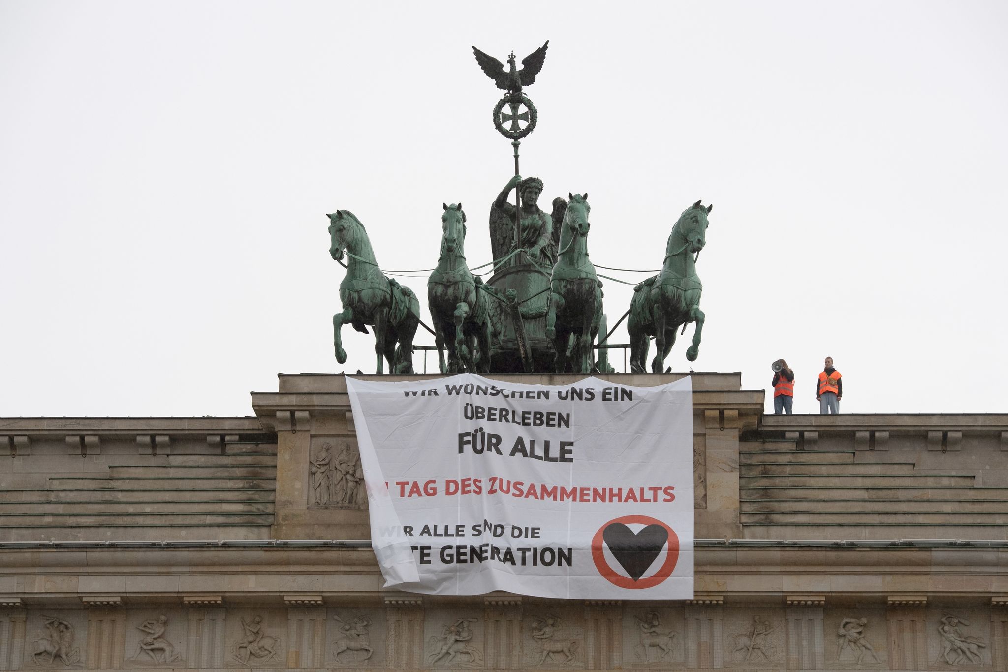 Ein Transparent mit dem Schriftzug «Wir wünschen uns ein Überleben für alle» hängt am Brandenburger Tor.