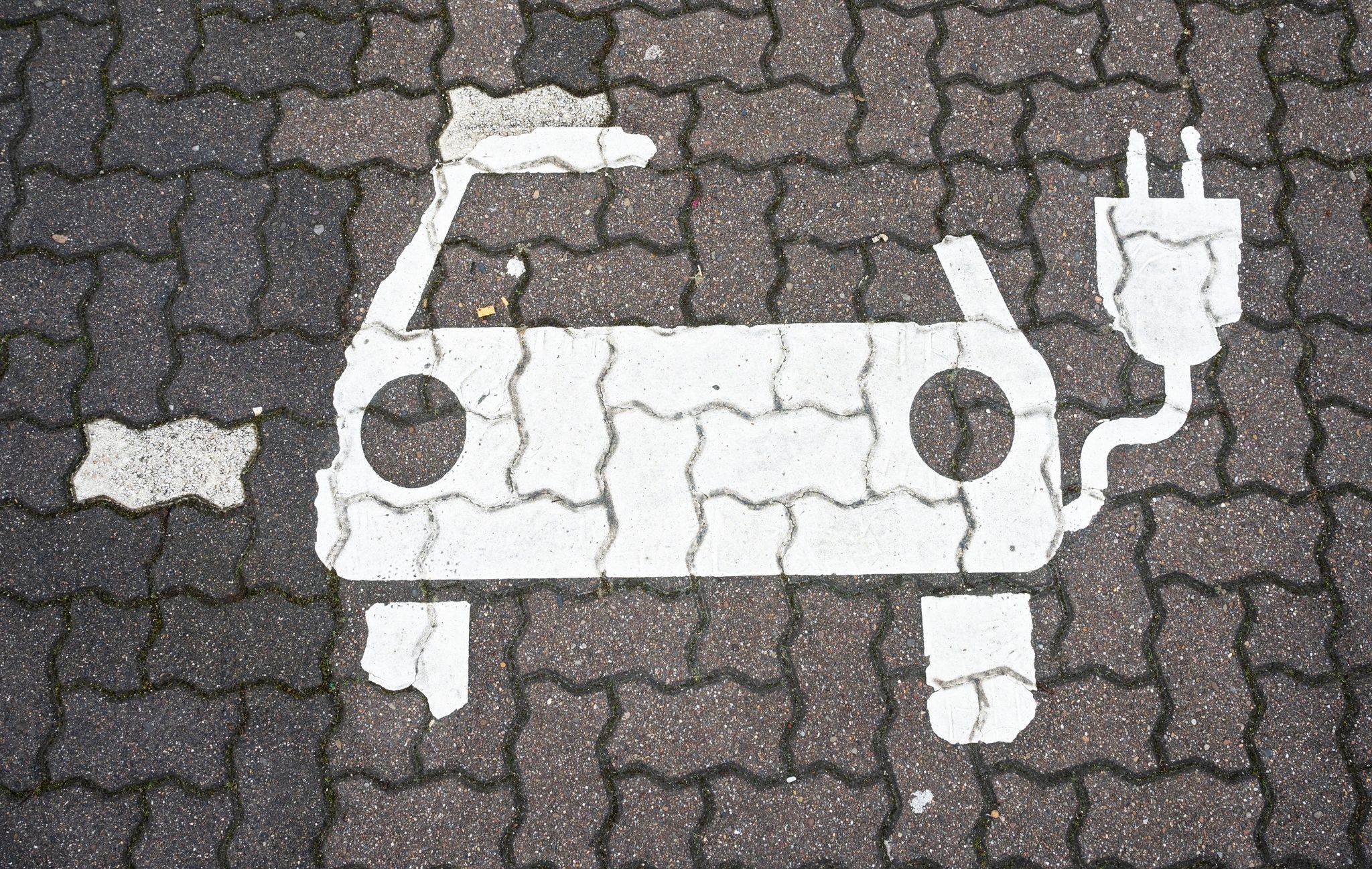 Ein Symbol für E-Autos ist auf einem Parkplatz zu sehen.
