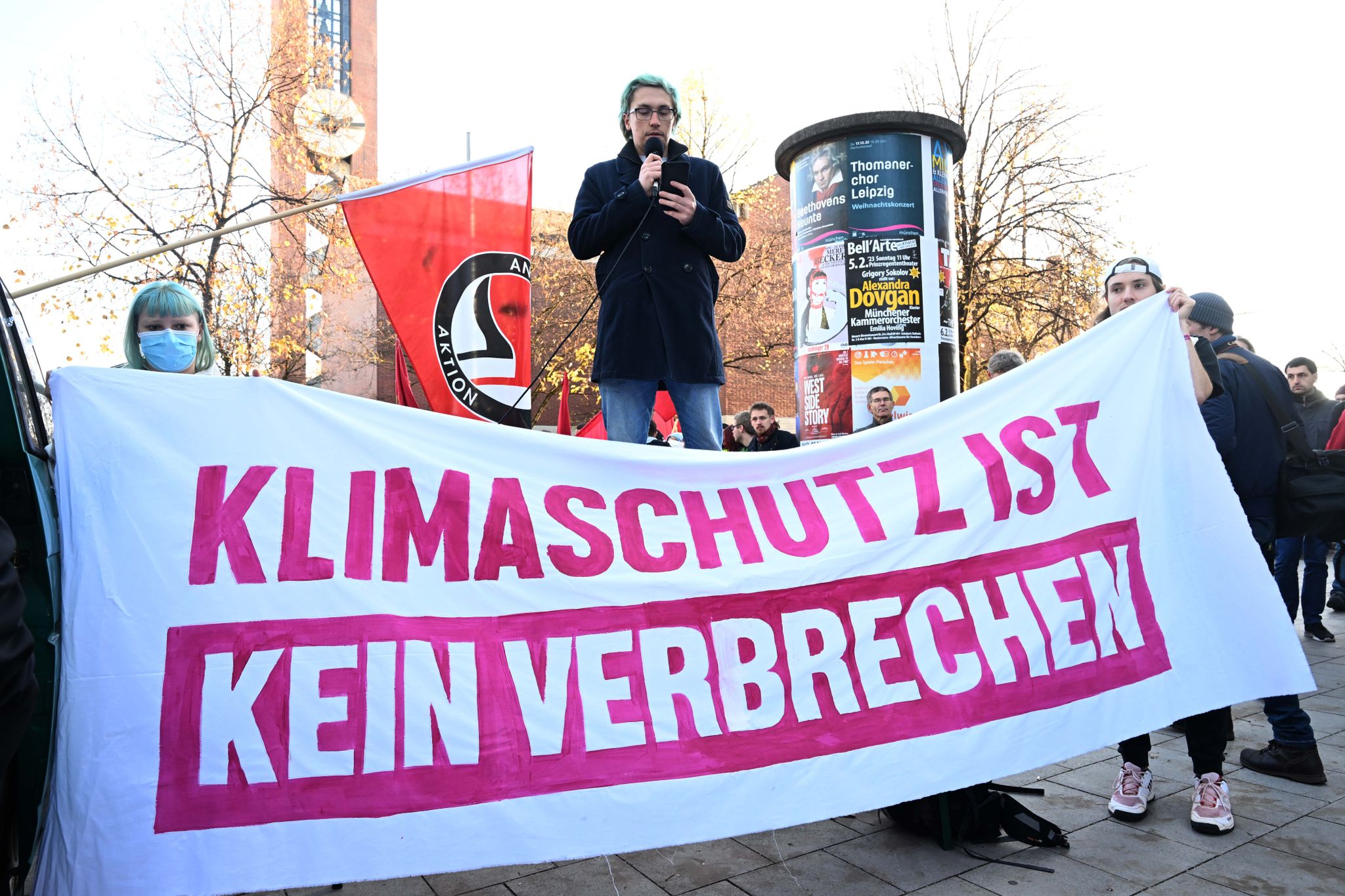 Ein Demonstrant spricht hinter einem Banner mit der Aufschrift «Klimaschutz ist kein Verbrechen».
