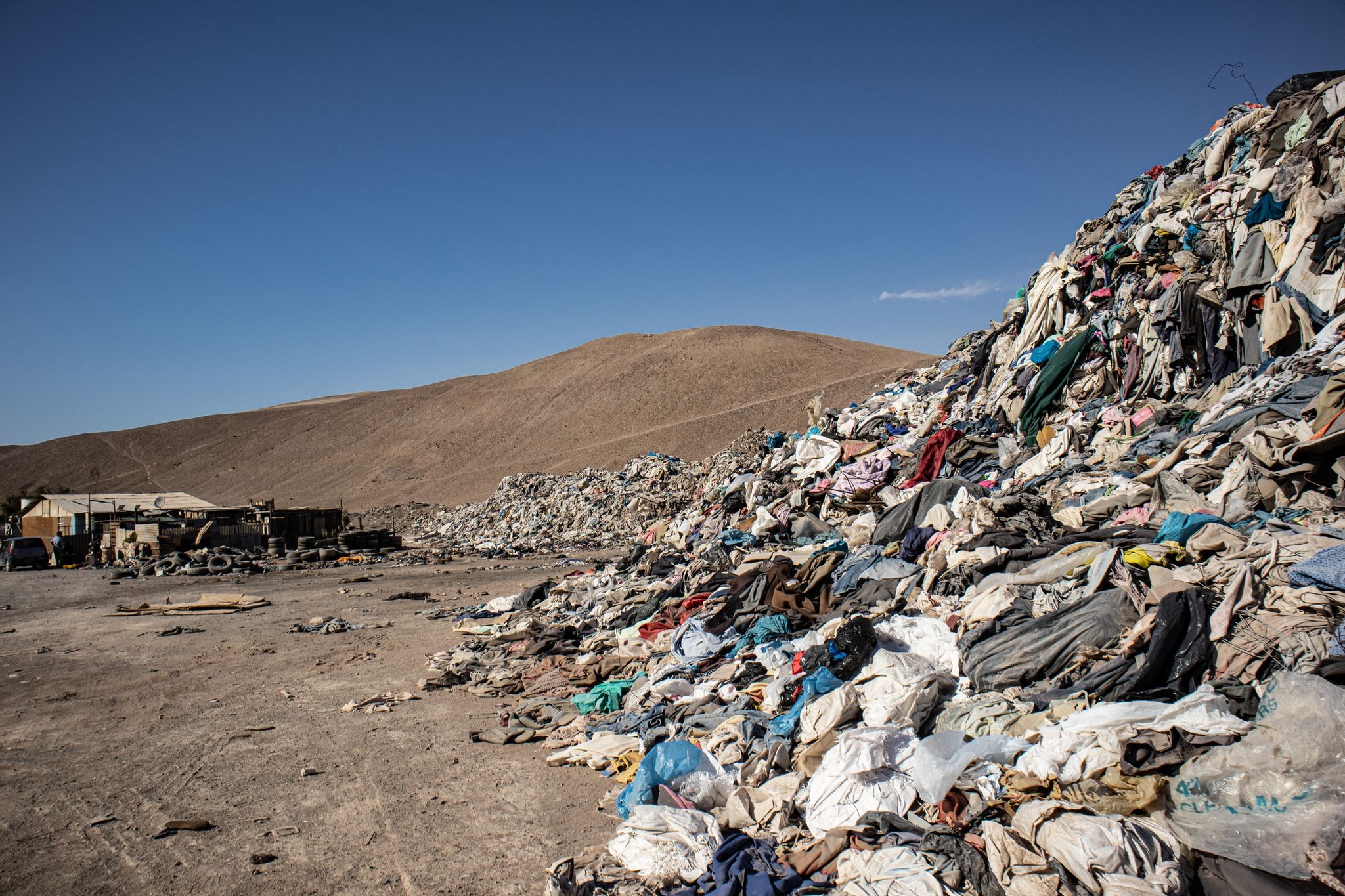 Gebrauchte Kleidungsstücke liegen in einer Müll-Deponie in der Wüste.