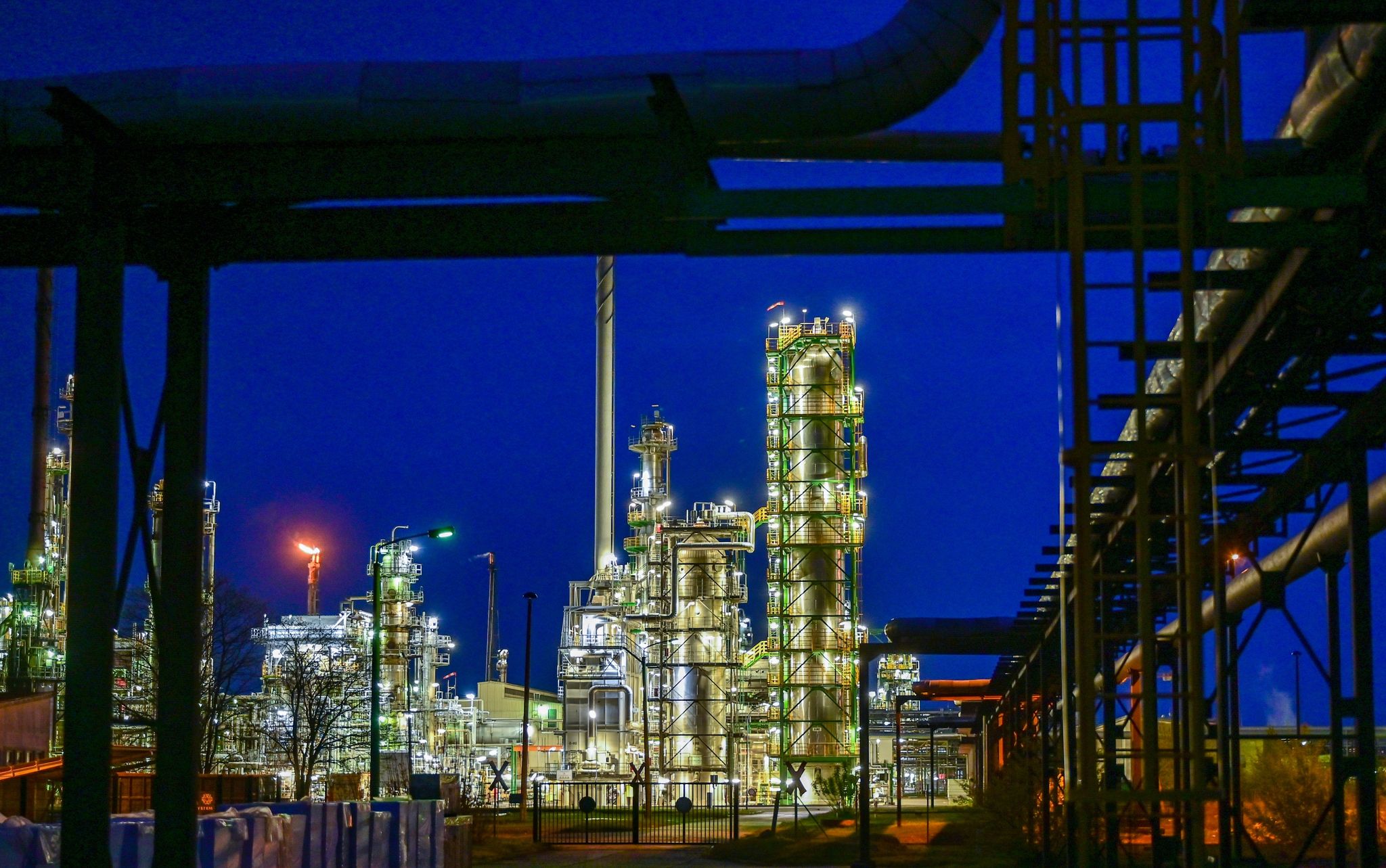 Die Anlagen der Erdölraffinerie auf dem Industriegelände der PCK-Raffinerie GmbH sind abends beleuchtet.