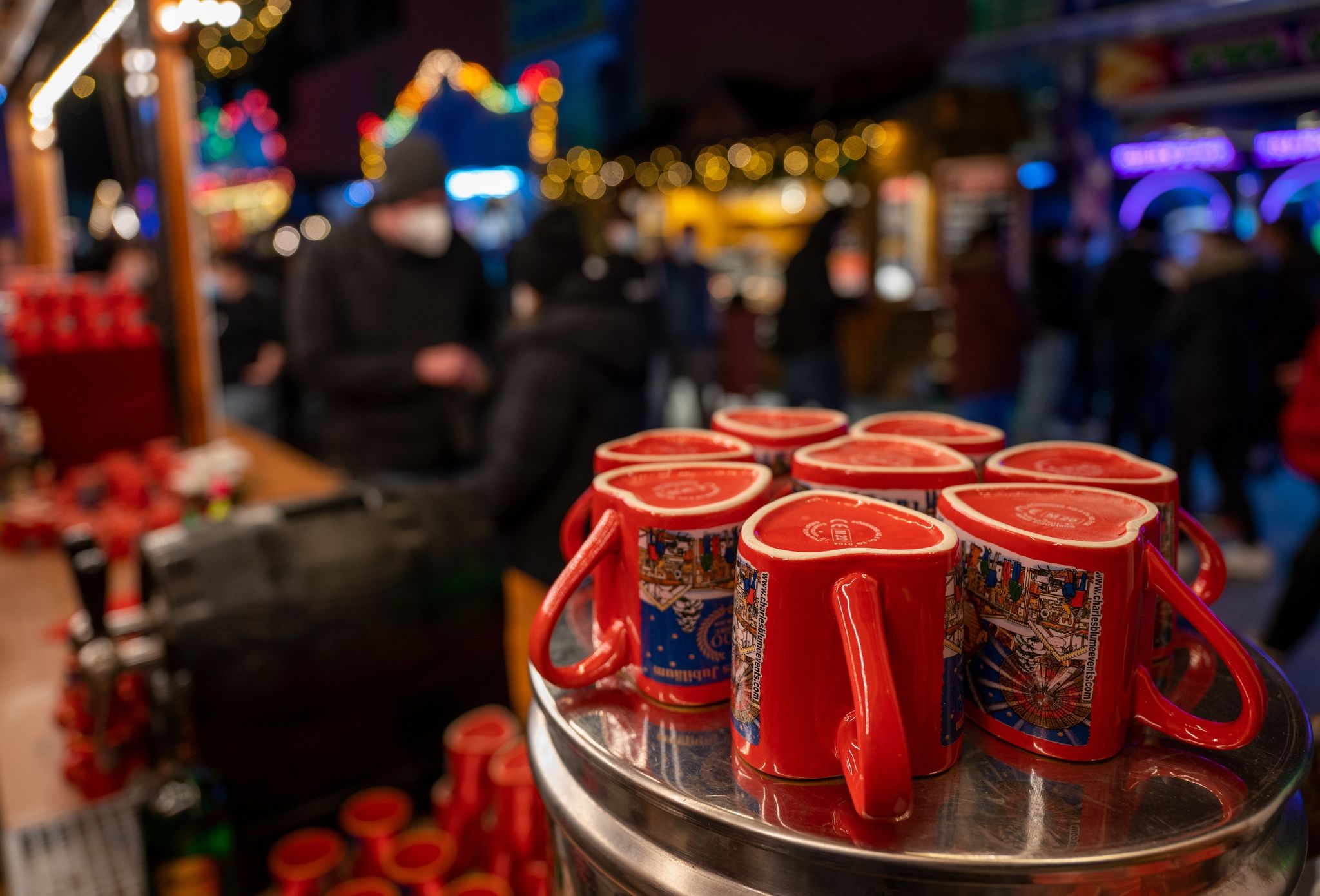 Glühweintassen stehen auf einem Weihnachtsmarkt vor einem Stand auf einem Tisch.