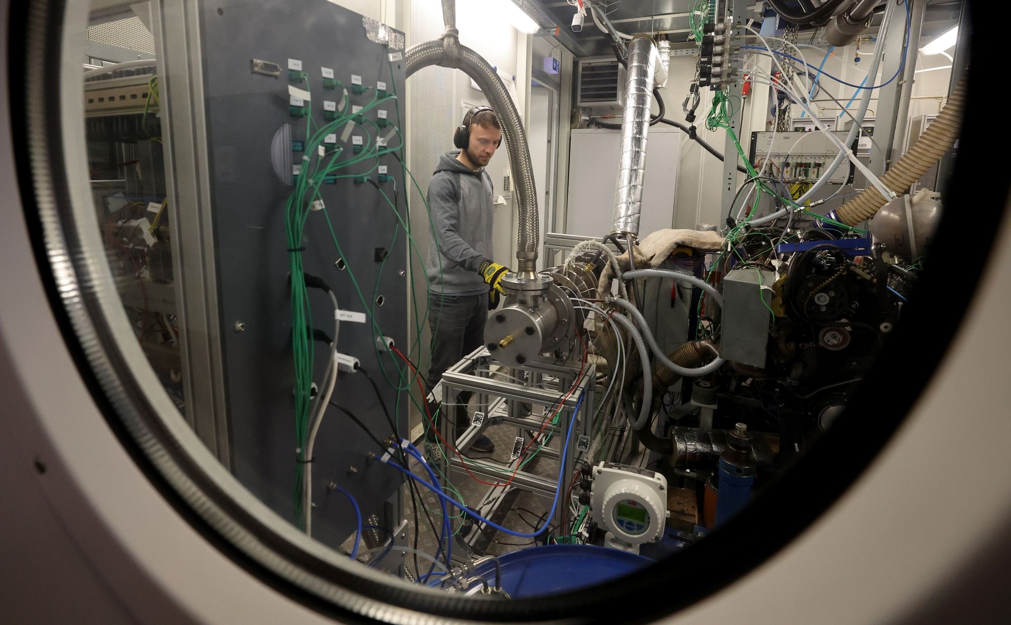 An einem Teststand in der Forschungshalle der Fakultät für Maschinenbau und Schiffstechnik der Universität Rostock kontrolliert der Doktorand Benedikt Gündling ein Verbrennungssystem, das die Emissionen eines Jet-Triebwerks ausstößt.