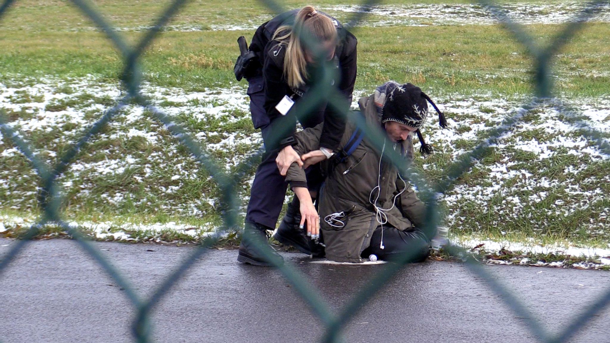 Eine Beamtin der Bundespolizei versucht einen Aktivisten der "Letzte Generation" von der Straße auf dem BER Flughafen zu entfernen.