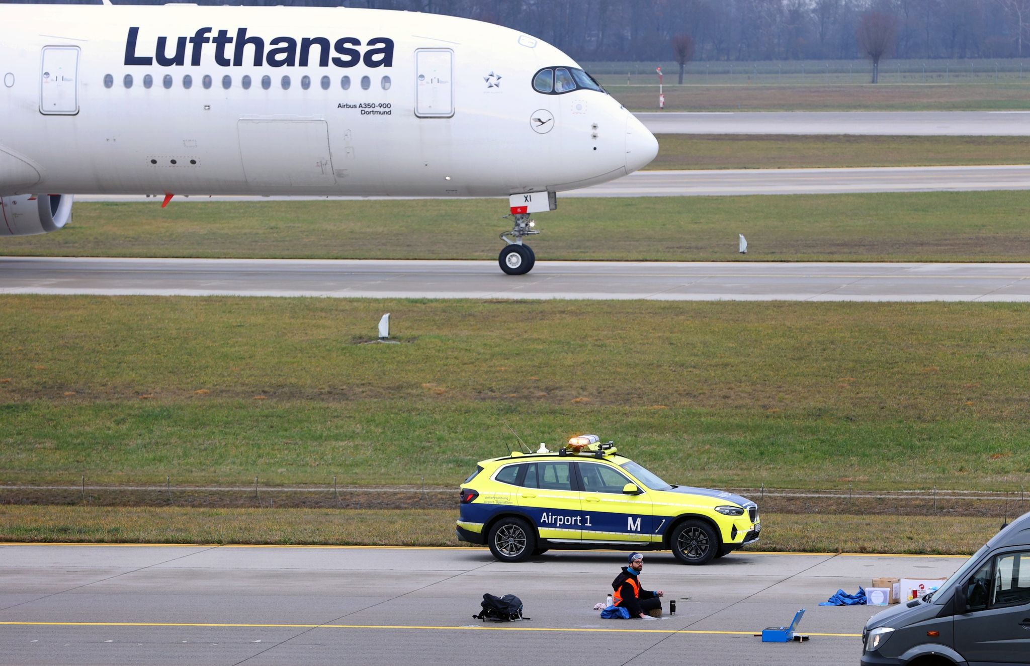 Ein letzter von vier Klimaaktivisten sitzt mit angeklebter Hand auf dem Zubringer einer Start-und Landebahn am Airport Franz-Josef-Strauß.