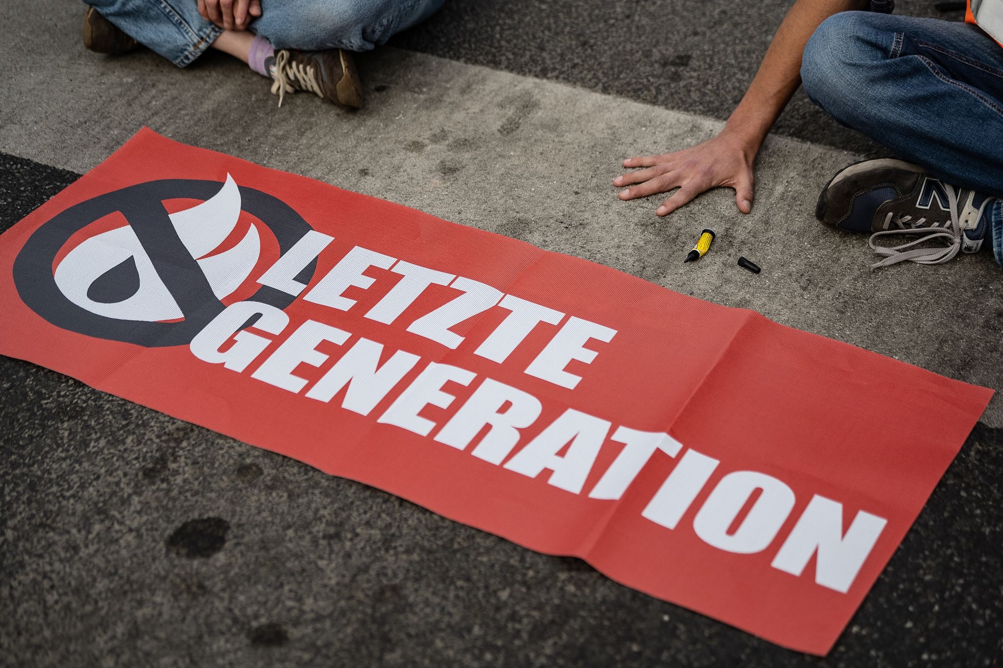 Ein Aktivist der Gruppe «Letzte Generation», der seine Hand selbst auf der Straße festgeklebt hat, blockiert eine Kreuzung.