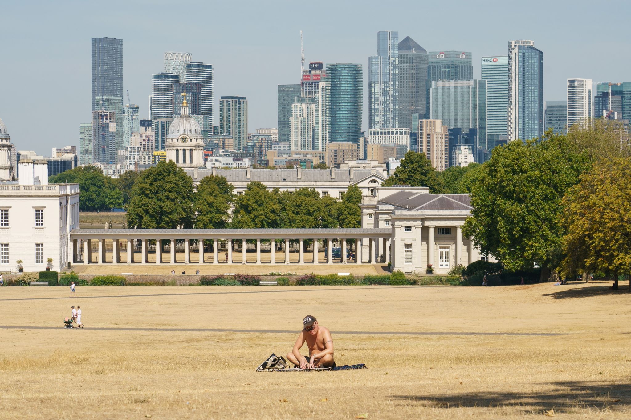 Ein Mann sonnt sich Mitte August auf einer vertrockneten Wiese vor der Kulisse Londons.