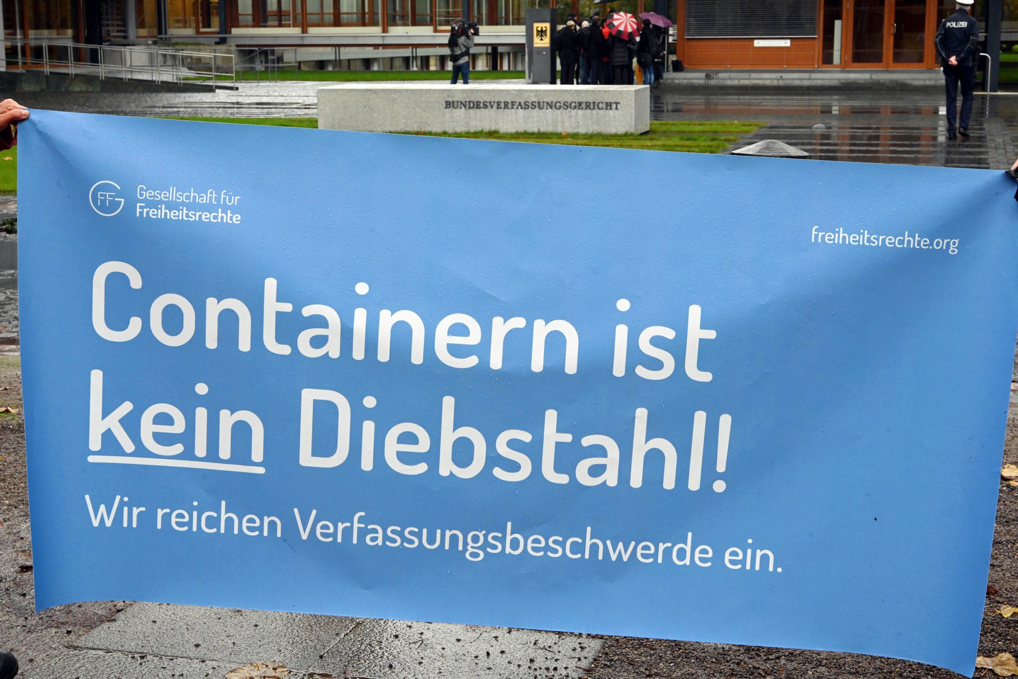 Vor dem Bundesverfassungsgericht wird ein ein Transparent gehalten auf dem steht „Containern ist kein Diebstahl!"