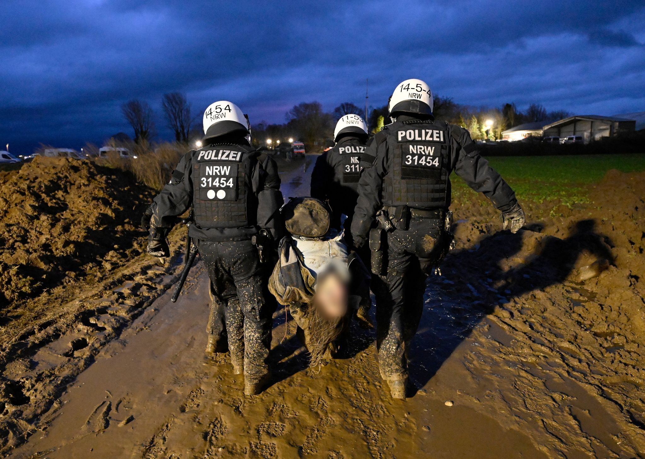 Polizisten tragen einen verletzten Demonstranten während der Demonstration von Klimaaktivisten am Rande des Braunkohletagebaus in Lützerath.