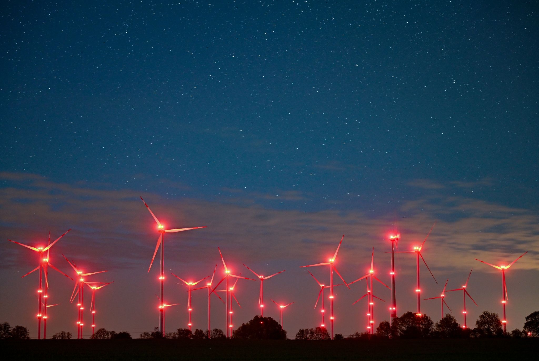 Die Positionslichter an Windenergieanlagen erhellen den Nachthimmel und die Landschaft.