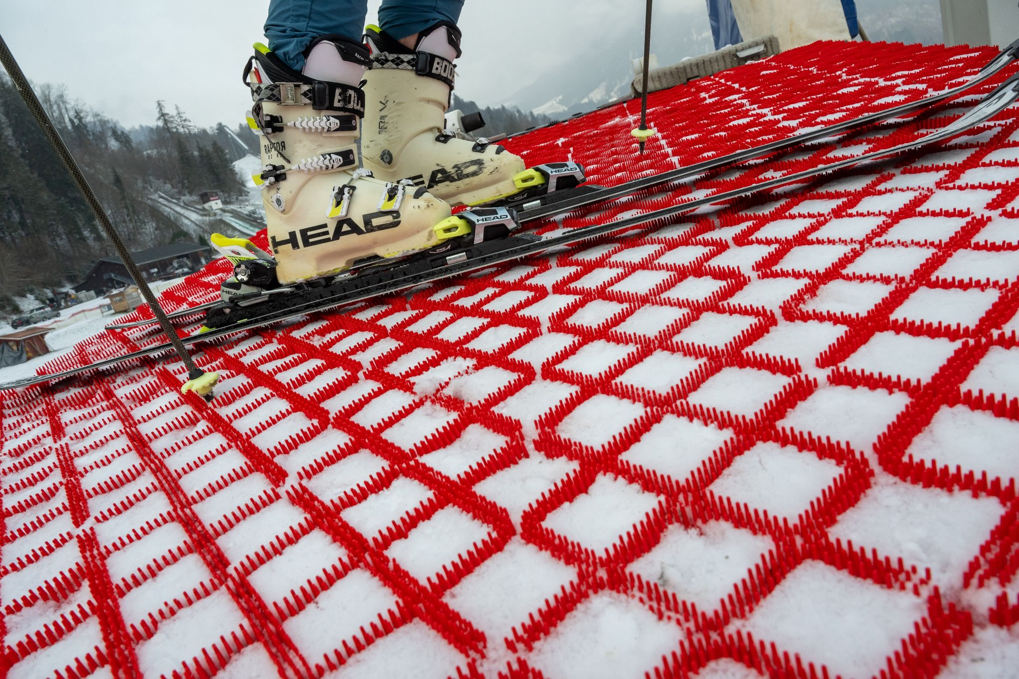 Ein Mann steht mit seinen Skiern auf einer Skipiste, die mit speziellen Kunststoff-Matten präpariert wurde. Die Matten können das ganze Jahr über zum Skifahren verwendet werden.