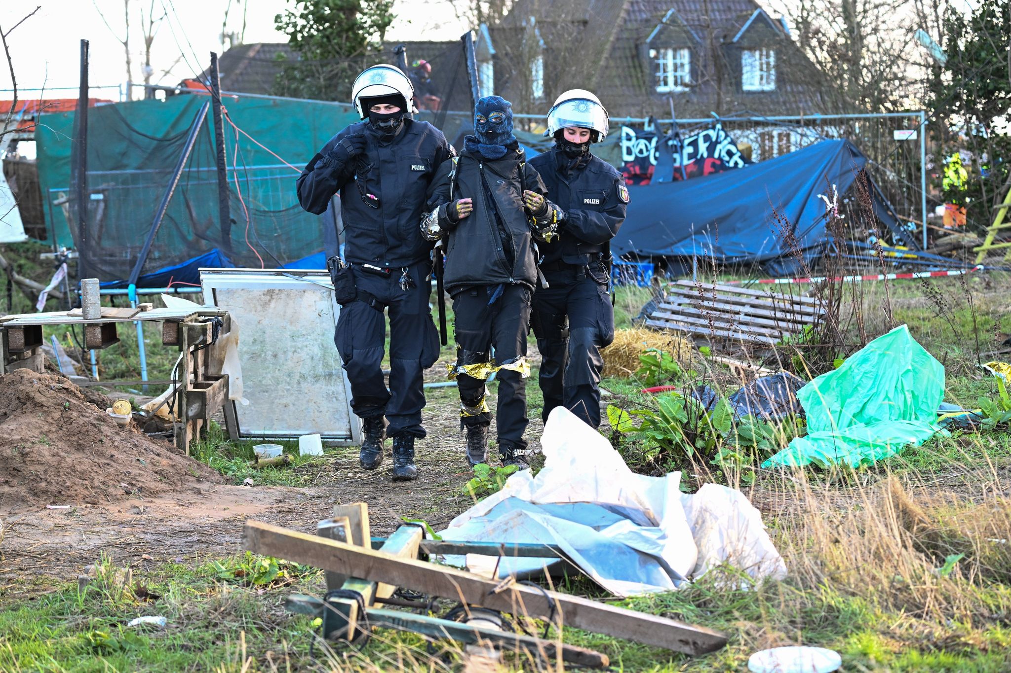 Polizisten führen einen Klimaaktivisten in Lützerath vom Gelände.