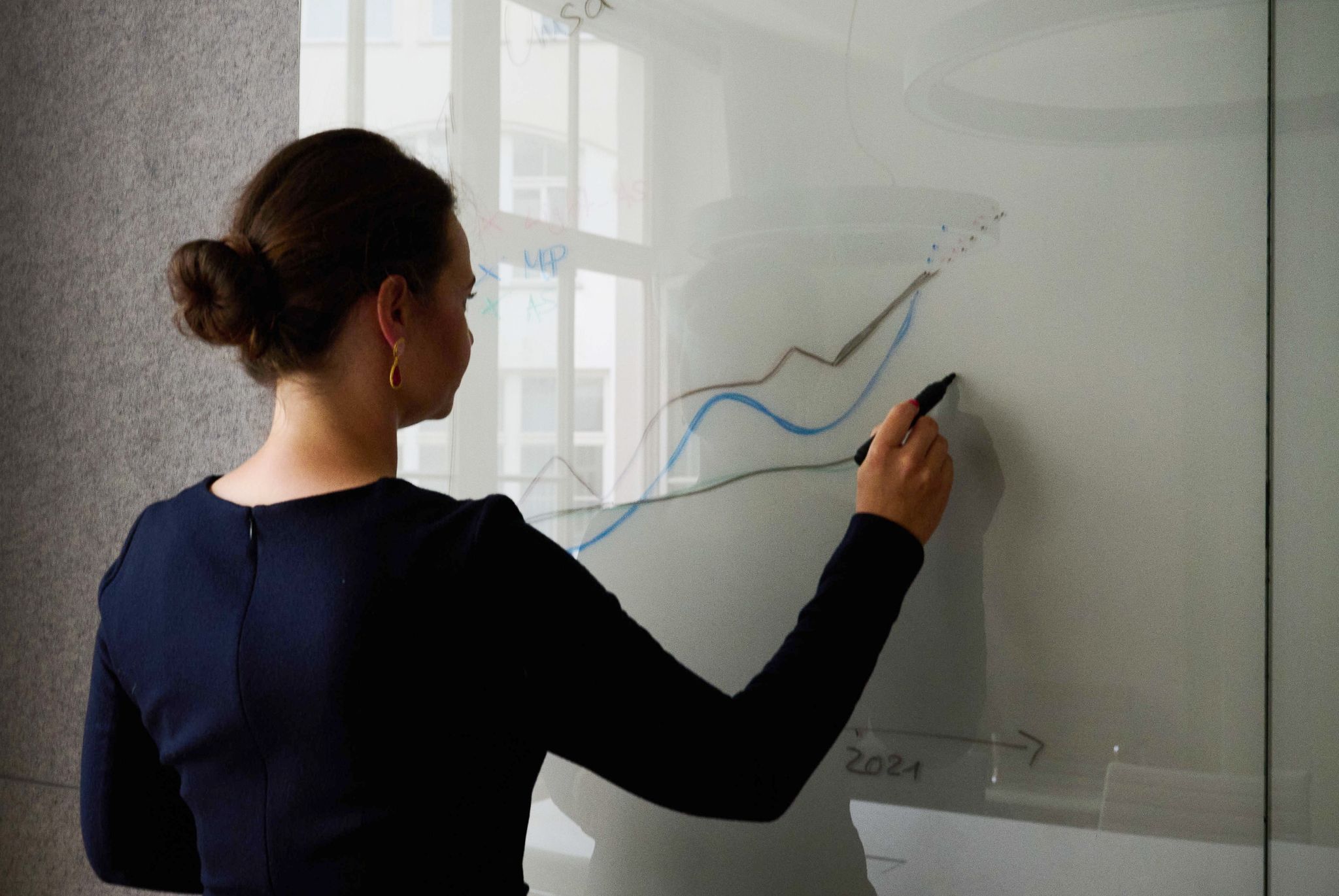 Eine Frau steht an einem Whiteboard in einem Konferenzraum.