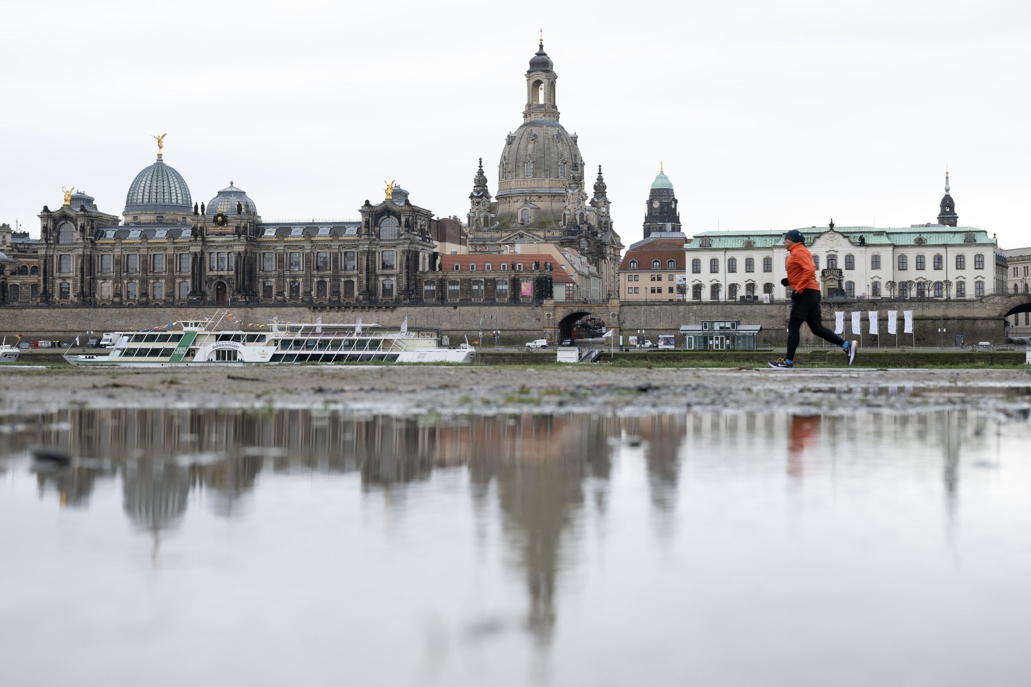 Ein Läufer am Ufer der Elbe vor der Kulisse der Altstadt.