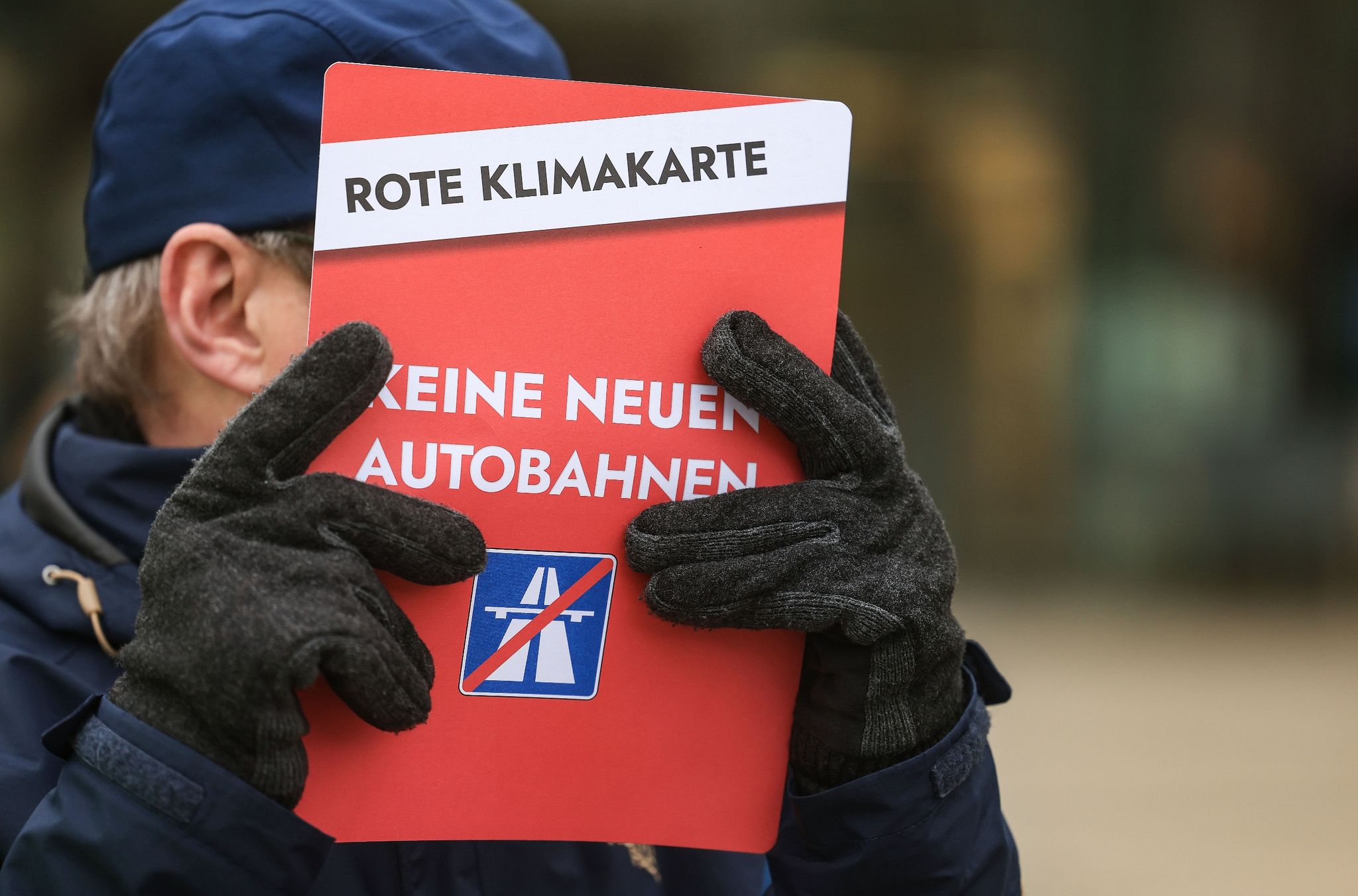Ein Mann hält ein Plakat mit der Aufschrift «Keine neuen Autobahnen».