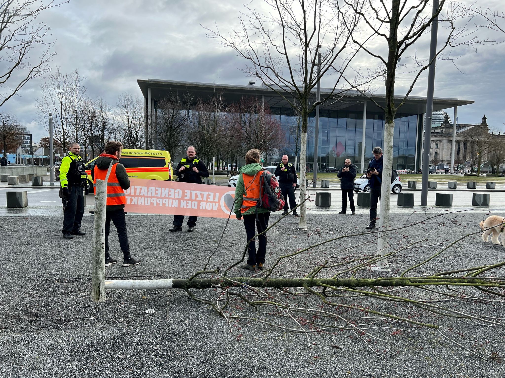 Klimaschutz-Demonstranten stehen an einem gefällten Baum am Bundeskanzleramt.