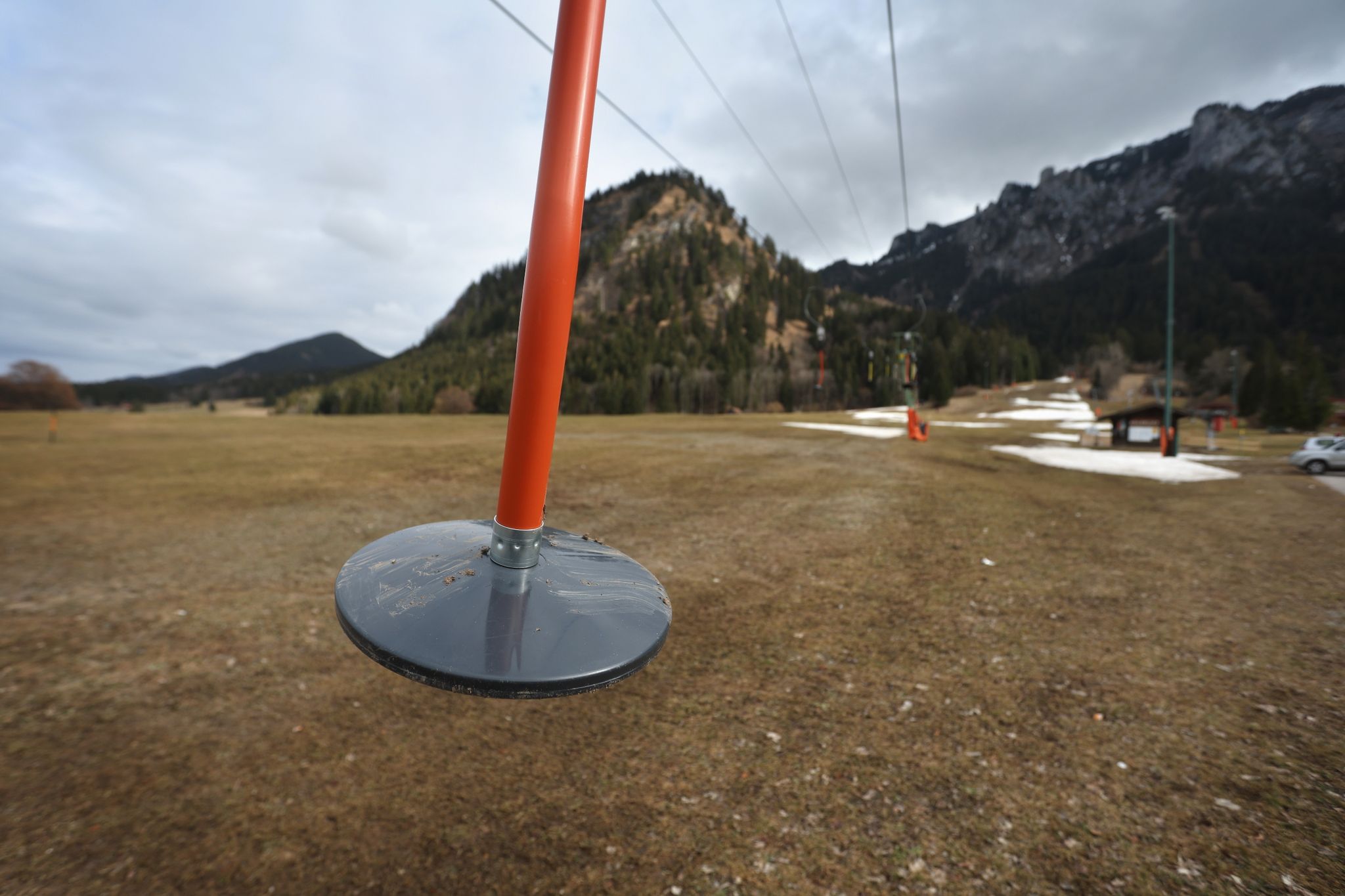 Teller eines Schleppliftes baumeln unbesetzt  an einer Skipiste im bayerischen Schwangau, auf der noch Reste von Kunstschnee zu sehen sind.