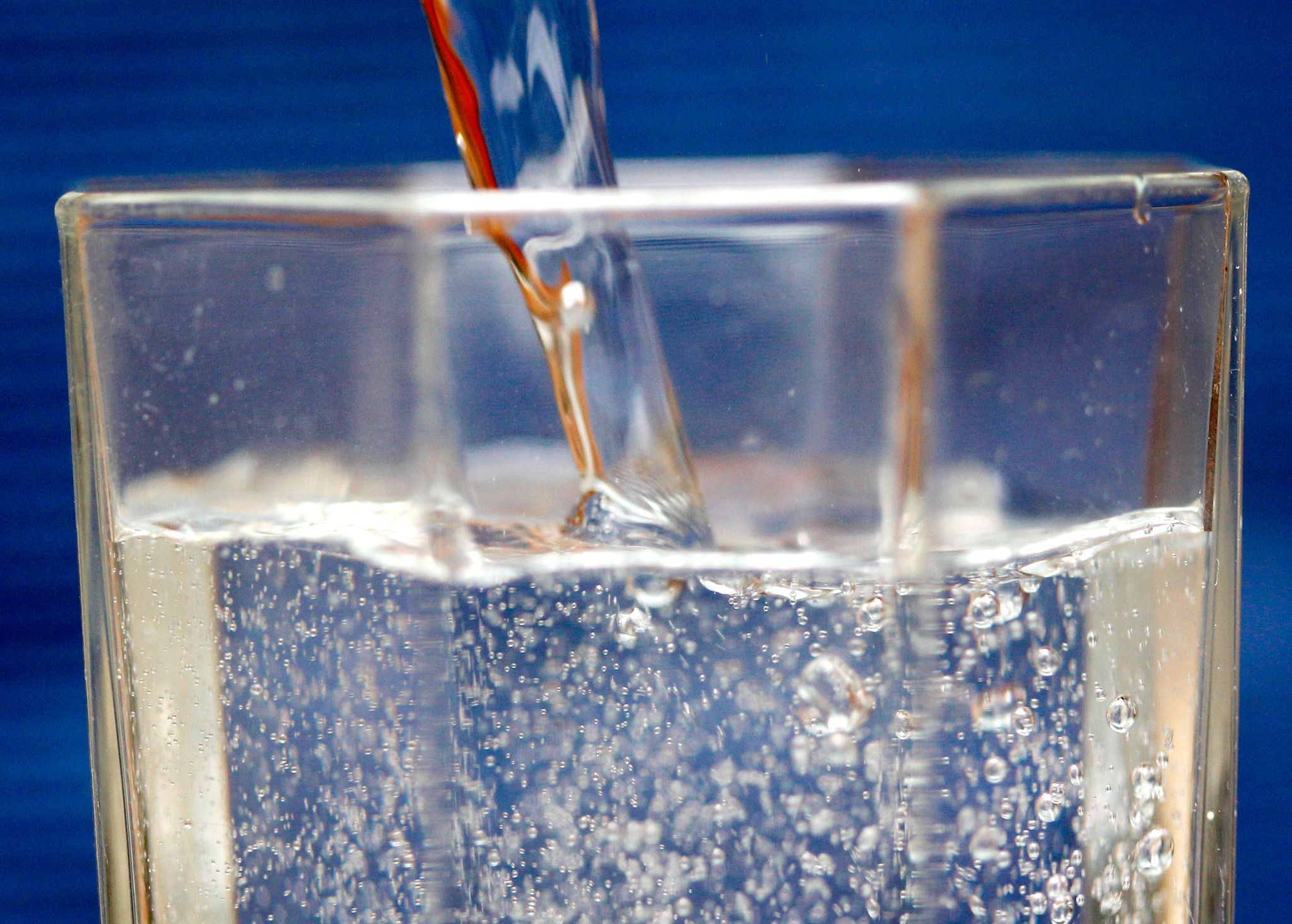 Mineralwasser wird in ein Wasserglas gegossen.
