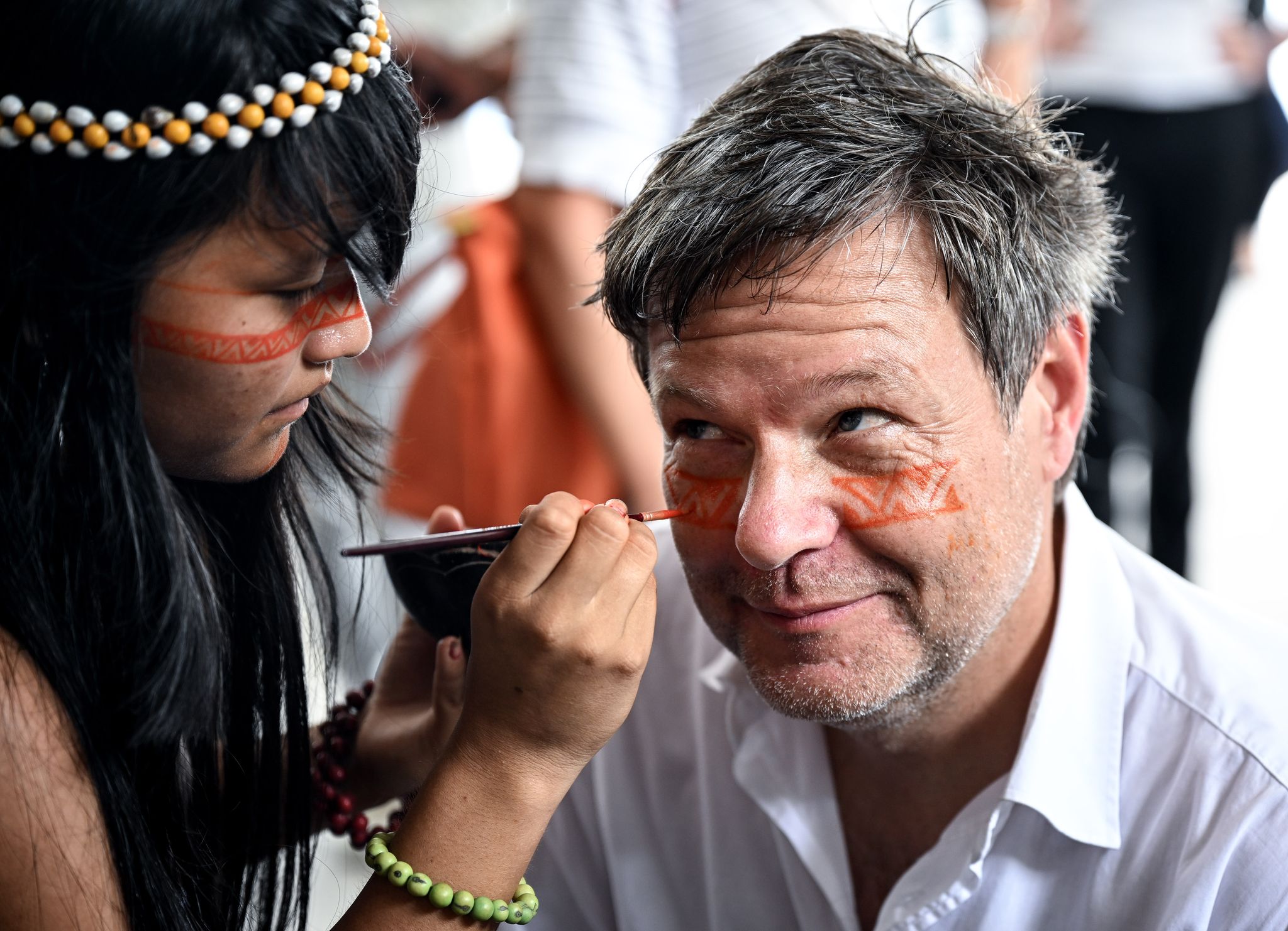 Ein Symbol des Willkommens und des Schutzes: Ein Mädchen malt Bundeswirtschaftsminister Robert Habeck mit einer rötlichen Naturfarbe ein Zeichen unter die Augen.