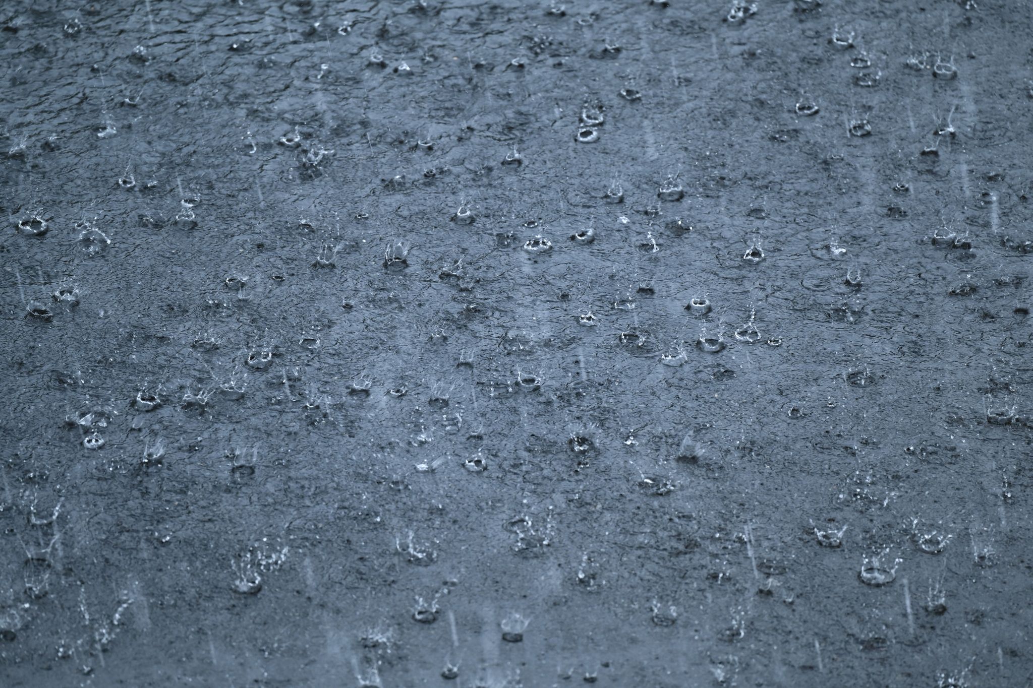 Starkregen prasselt während eines Gewitters auf eine Straße.