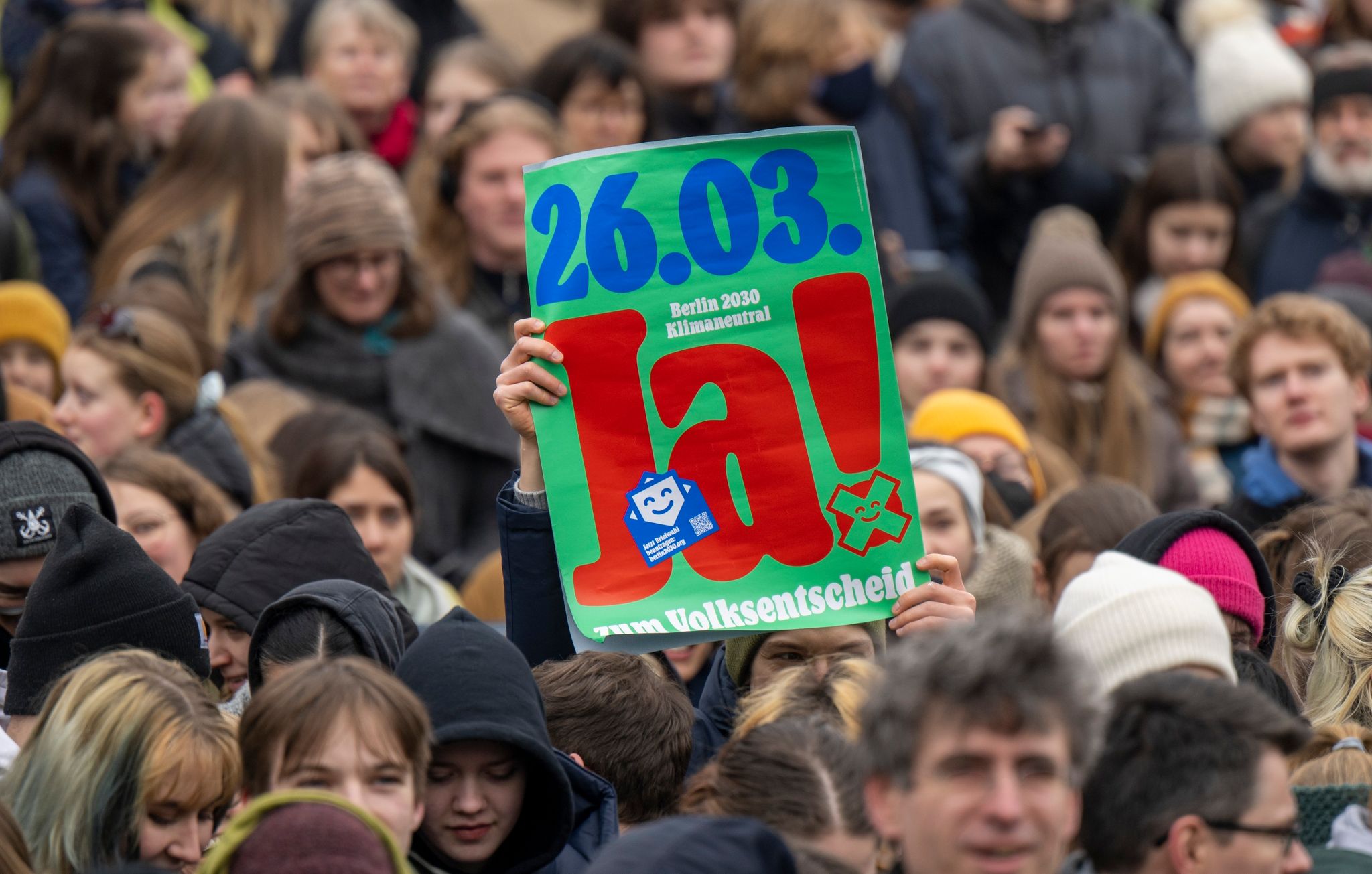 Ein Teilnehmer einer Demonstration von Fridays for Future hält einen Plakat mit der Aufschrift „26.03. Berlin 2030 klimaneutral. Ja zum Volksentscheid“ hoch.