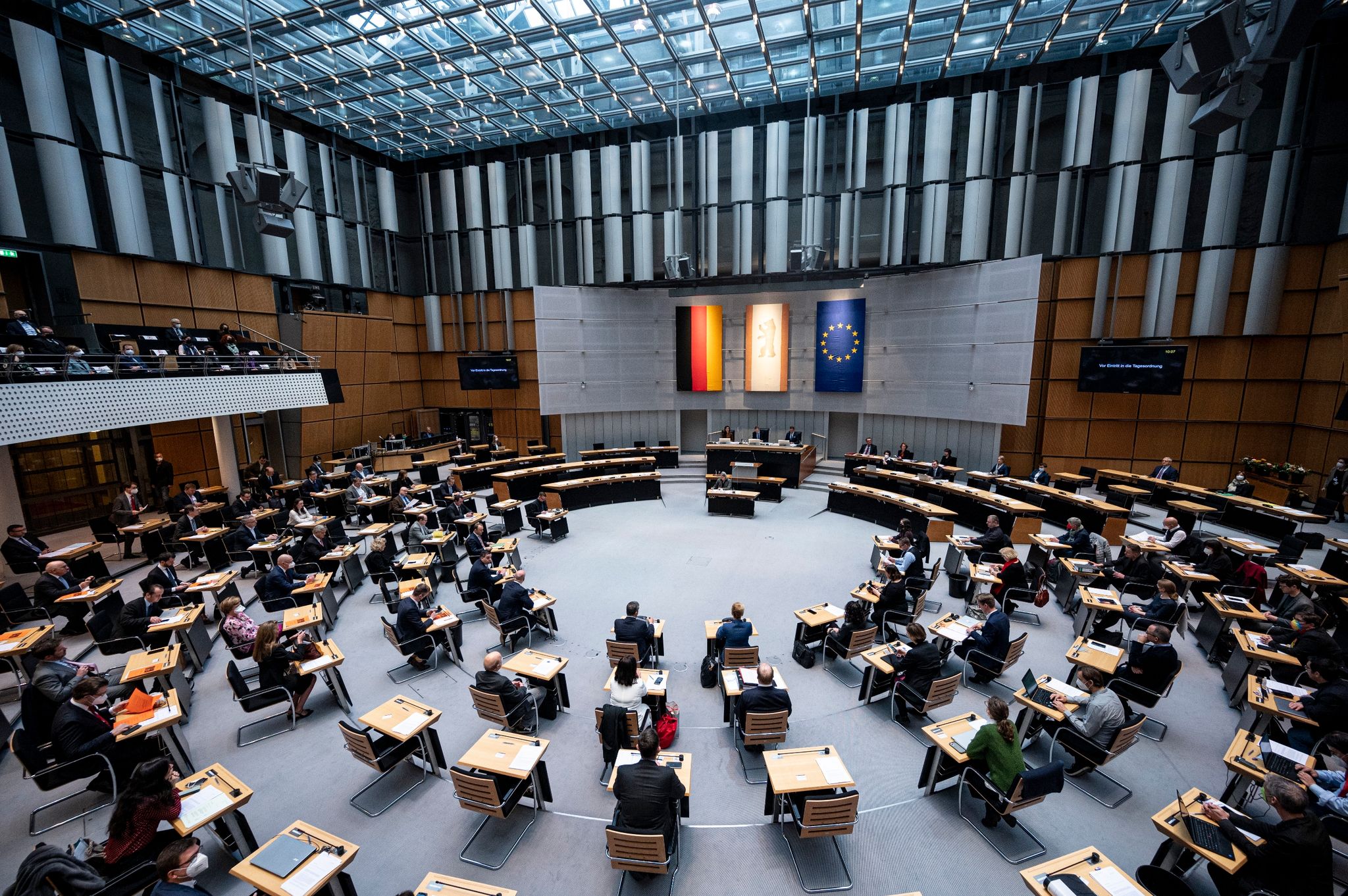Abgeordnete stehen im Plenarsaal des Berliner Abgeordnetenhauses.