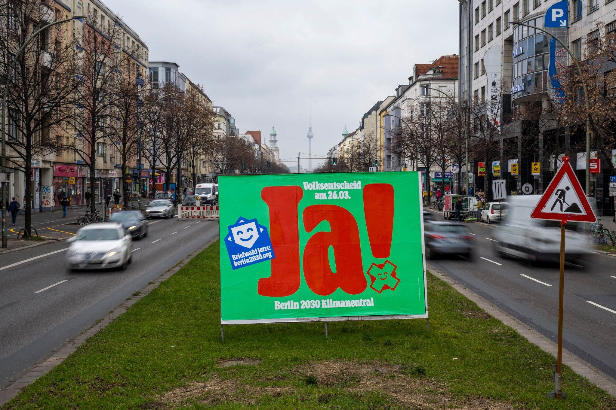 Ein Plakat mit der Aufschrift „Ja! - Berlin 2030 Klimaneutral“ steht auf der Frankfurter Allee.