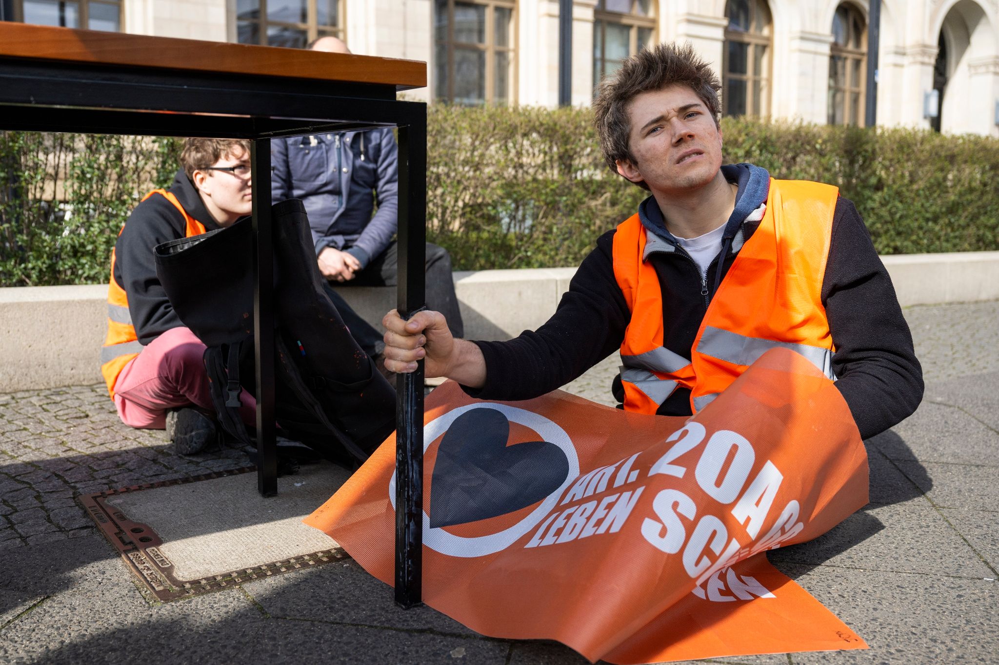 Klimaaktivist Henning Jeschke (r) sitzt bei einer Protestaktion vor dem Bundesverkehrsministerium.