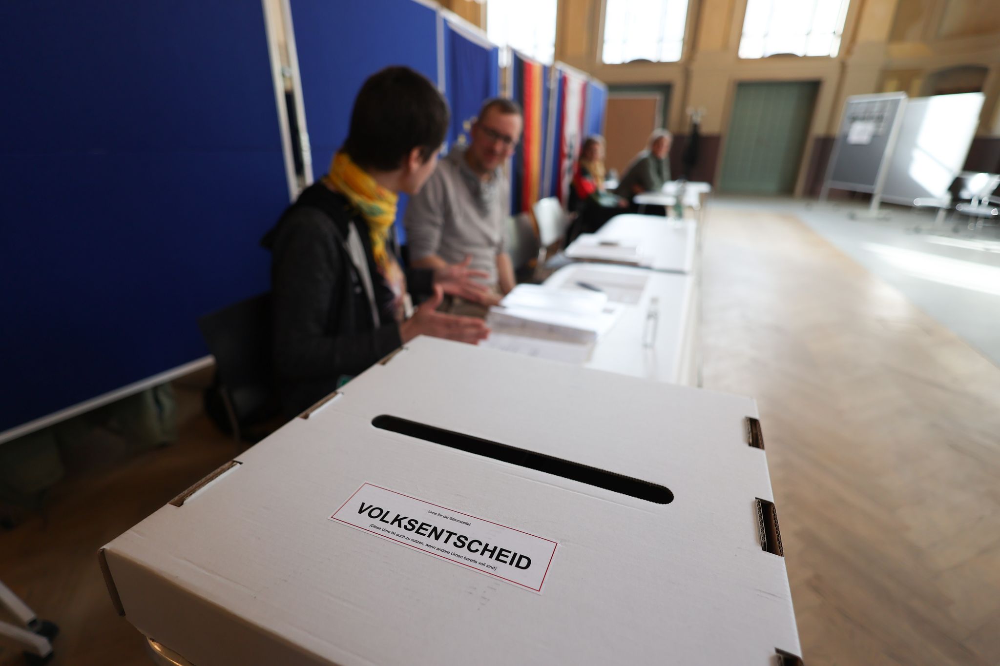 Wahlhelfer sitzen vor einer Wahlurne in einem Wahllokal in Berlin-Weissensee.