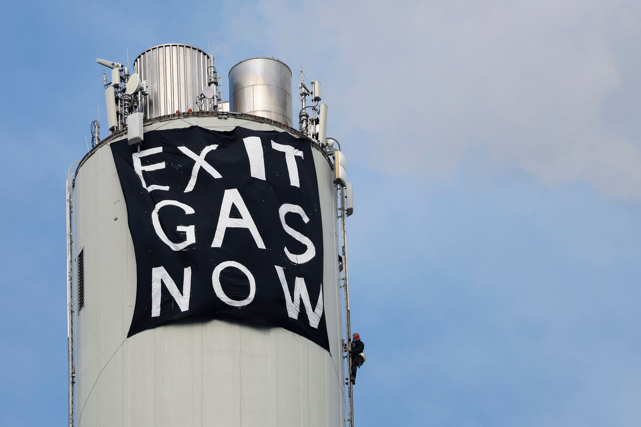 Ein Klimaaktivist befestigt ein Protestbanner „EXIT GAS NOW“ am Schornstein des Erdgaskraftwerk in Erlangen.