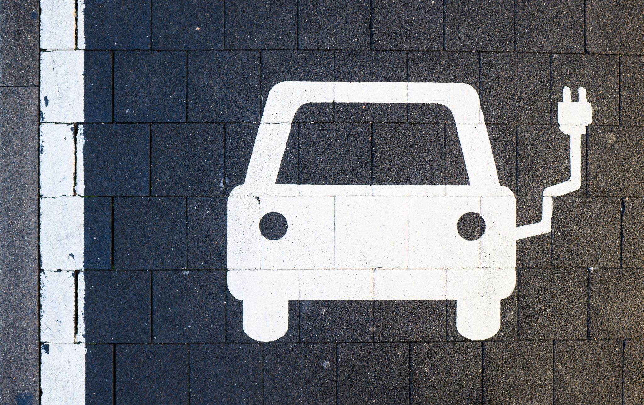 Ein Symbol markiert einen Parkplatz an einer Ladesäule für Elektroautos.