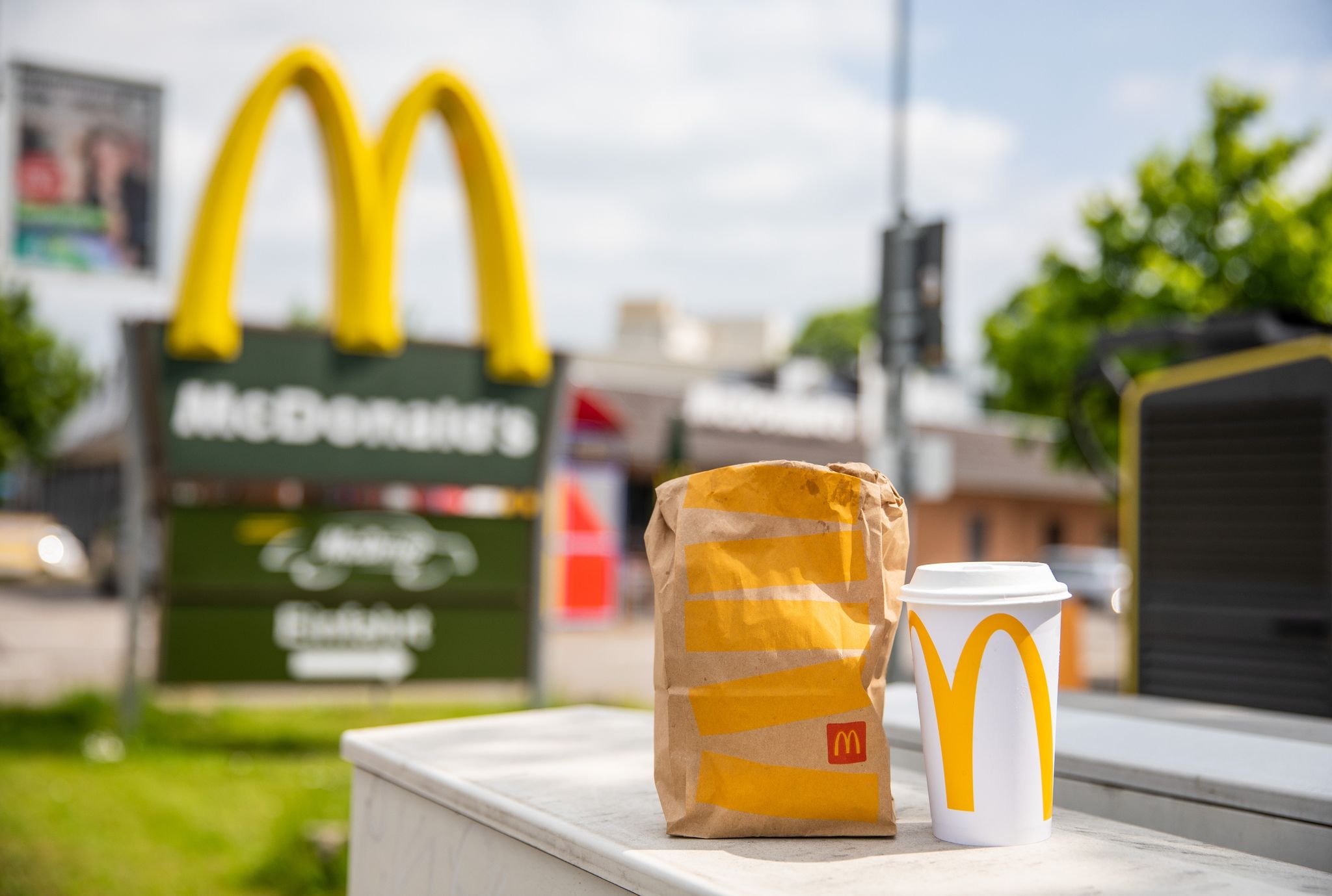 Eine McDonald's To-Go-Tüte und ein dazugehöriger To-Go-Becher stehen vor einer Tübinger McDonald's Filiale.