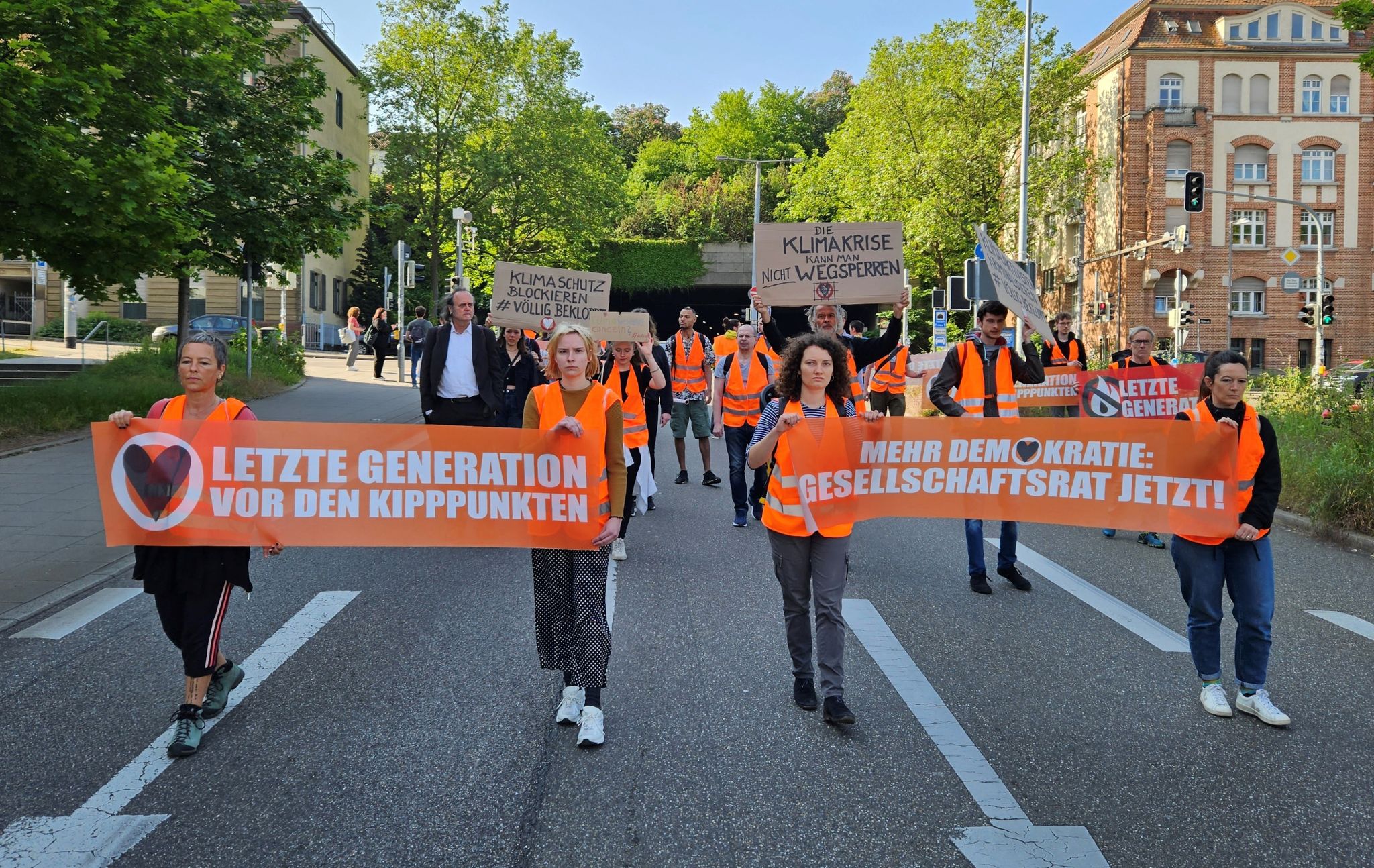 Aktivistinnen und Unterstützer der Gruppierung Letzte Generation demonstrieren in Stuttgart mit Transparenten.