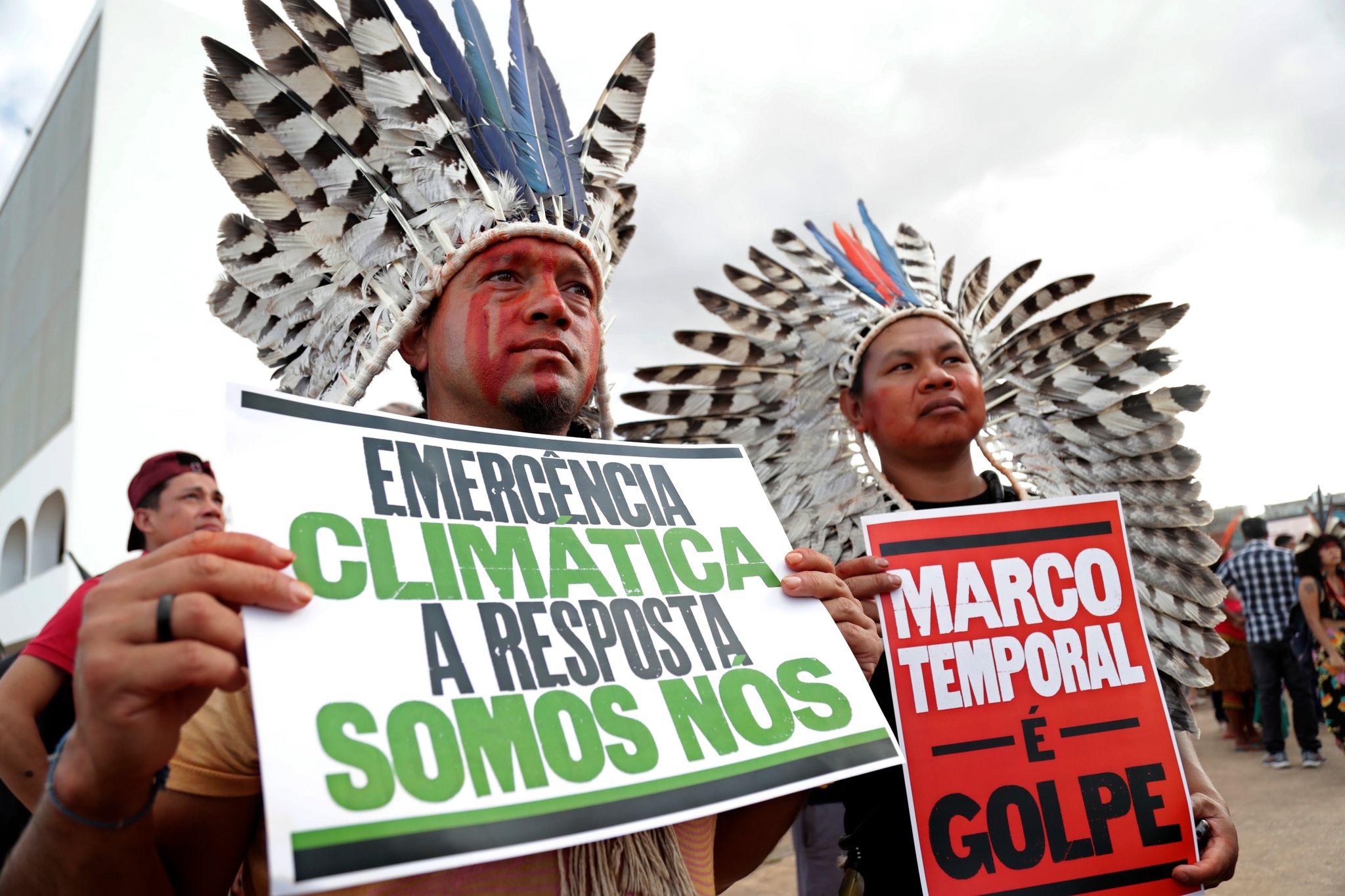 «Klima-Notstand - die Antwort sind wir» steht auf dem Plakat (r) eines indigenen Demonstranten, der in Brasilia gegen den Gesetzesentwurf zur Ausweisung von Schutzgebieten protestiert.