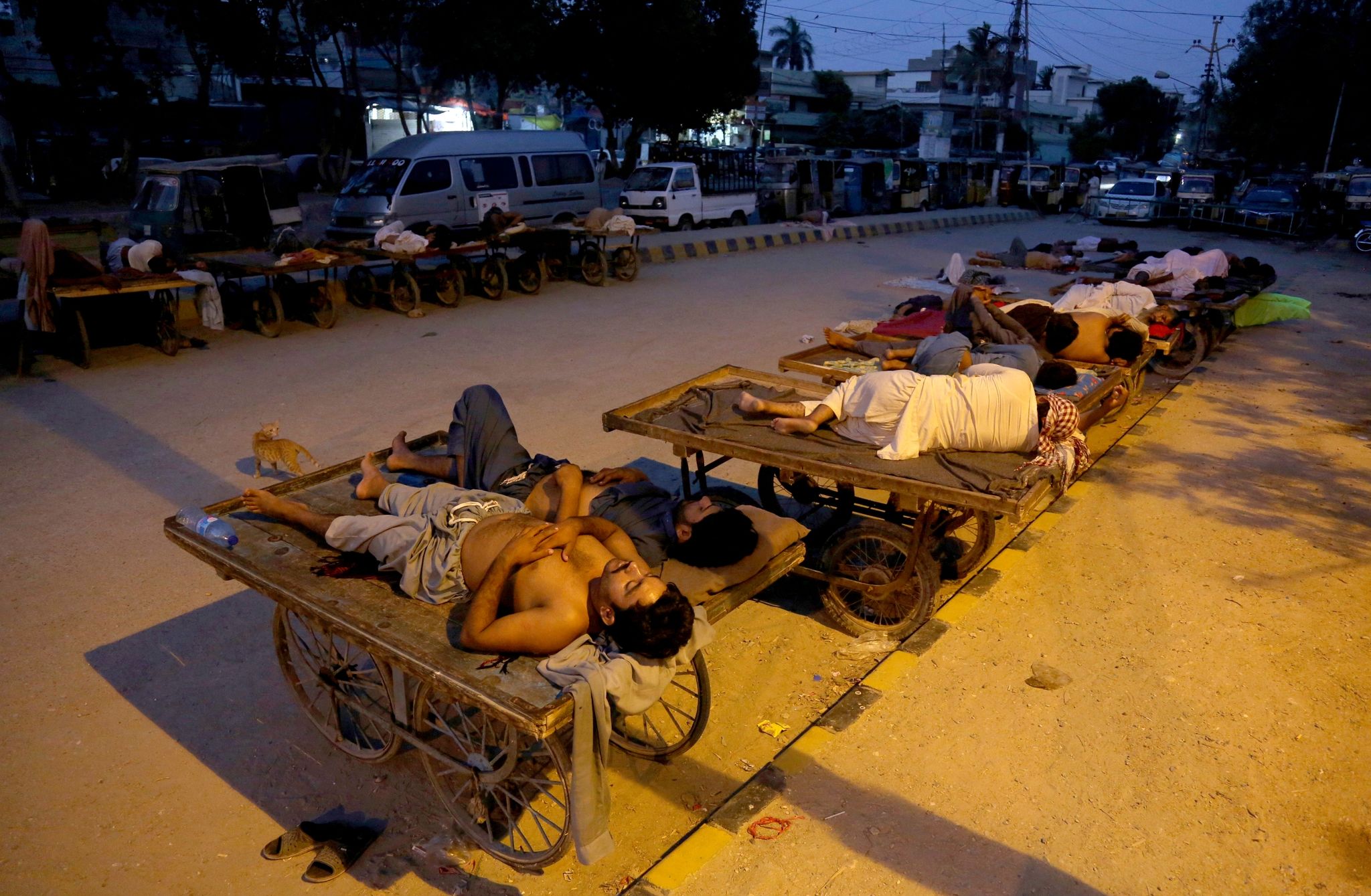 Verkäufer und Rikscha-Fahrer schlafen an einem heißen Sommermorgen im Freien.