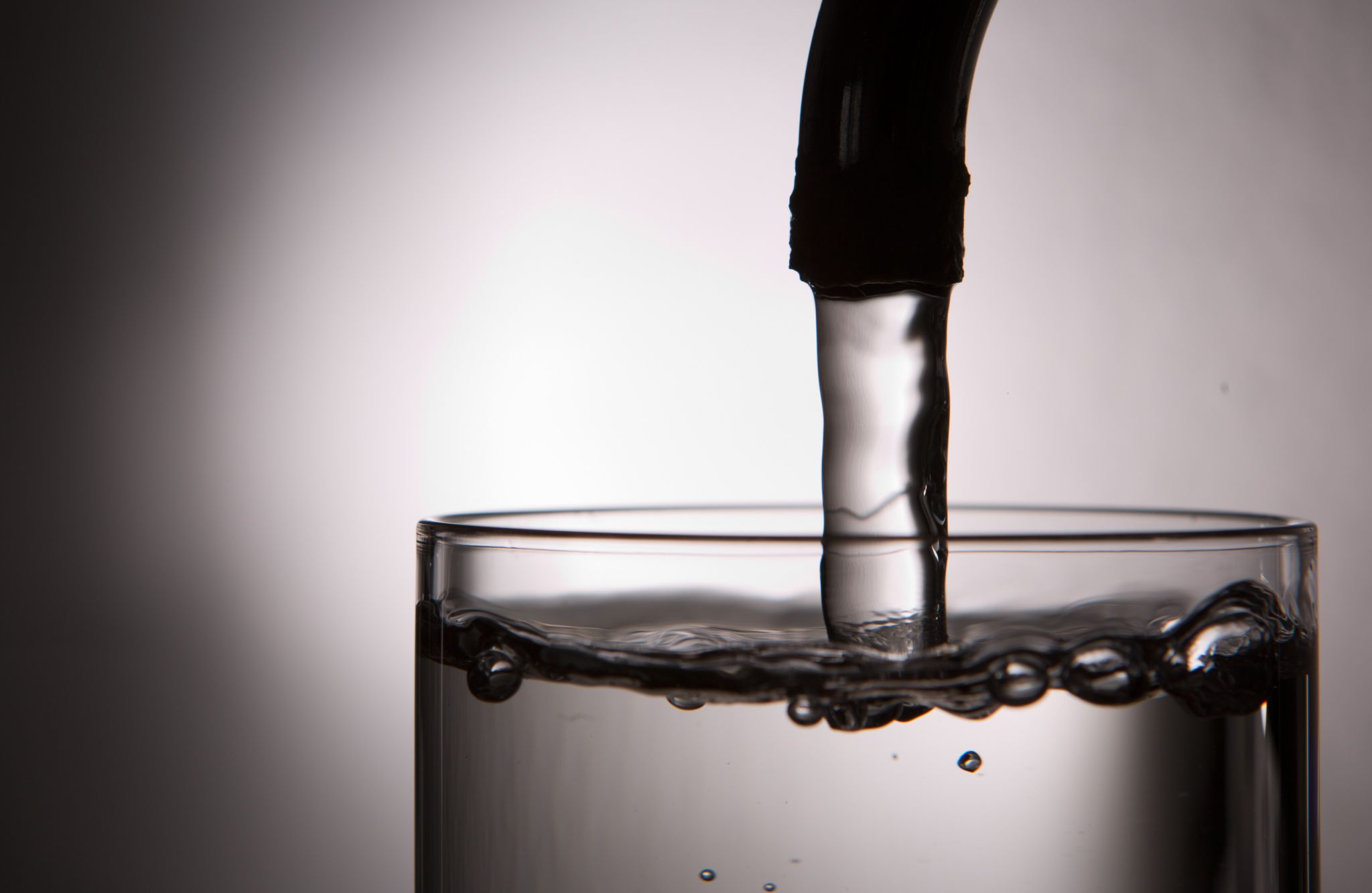 Leitungswasser läuft aus einem Wasserhahn in ein Glas.