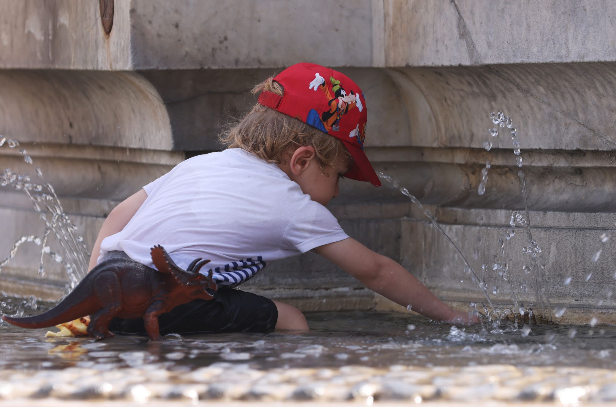 Ein Kind kühlt sich bei 38 Grad Celsius an einem Brunnen ab.