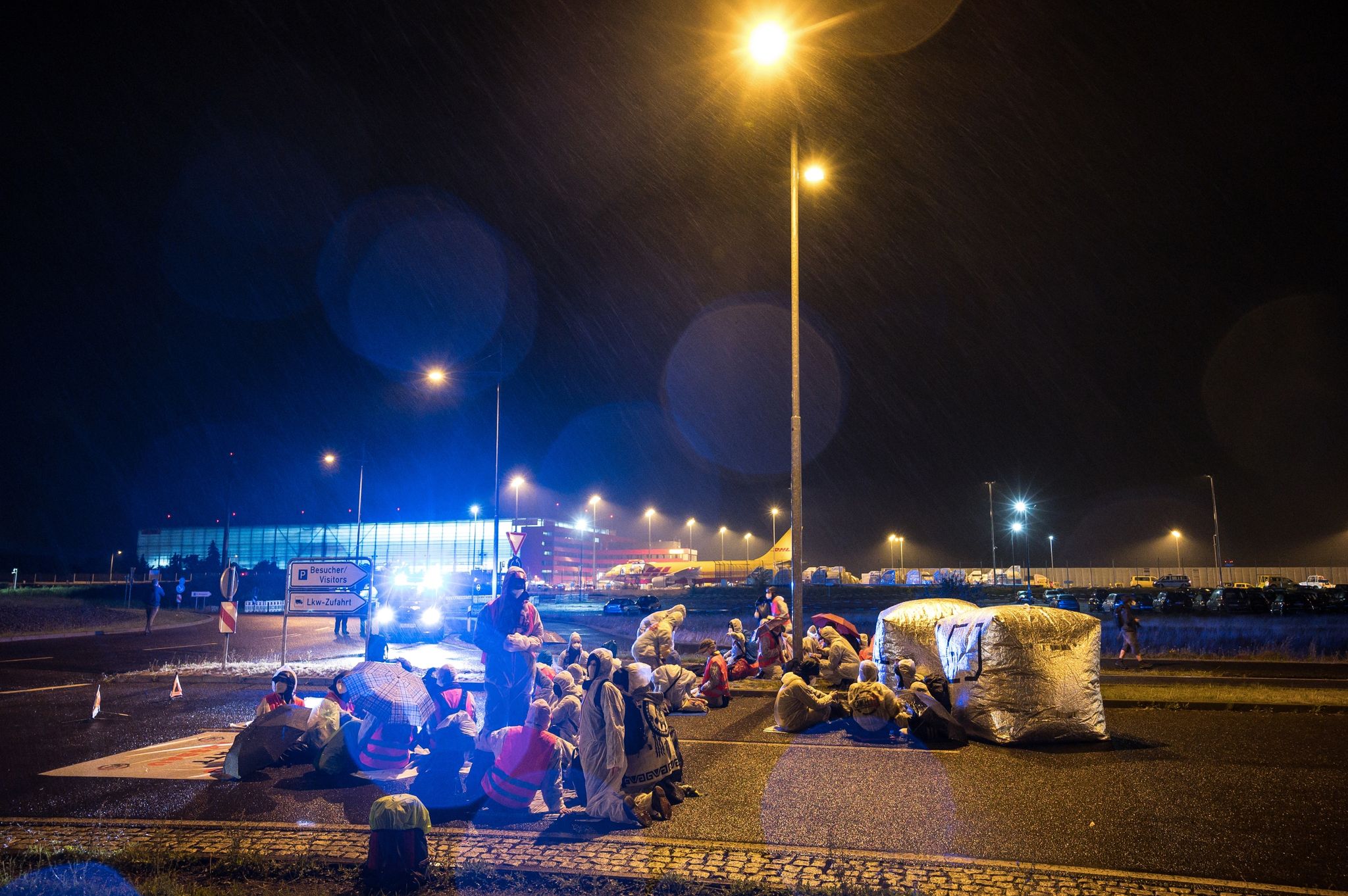 Aktivisten der Initiative "CancelLEJ" blockieren eine LKW Zufahrt des DHL-Terminals.