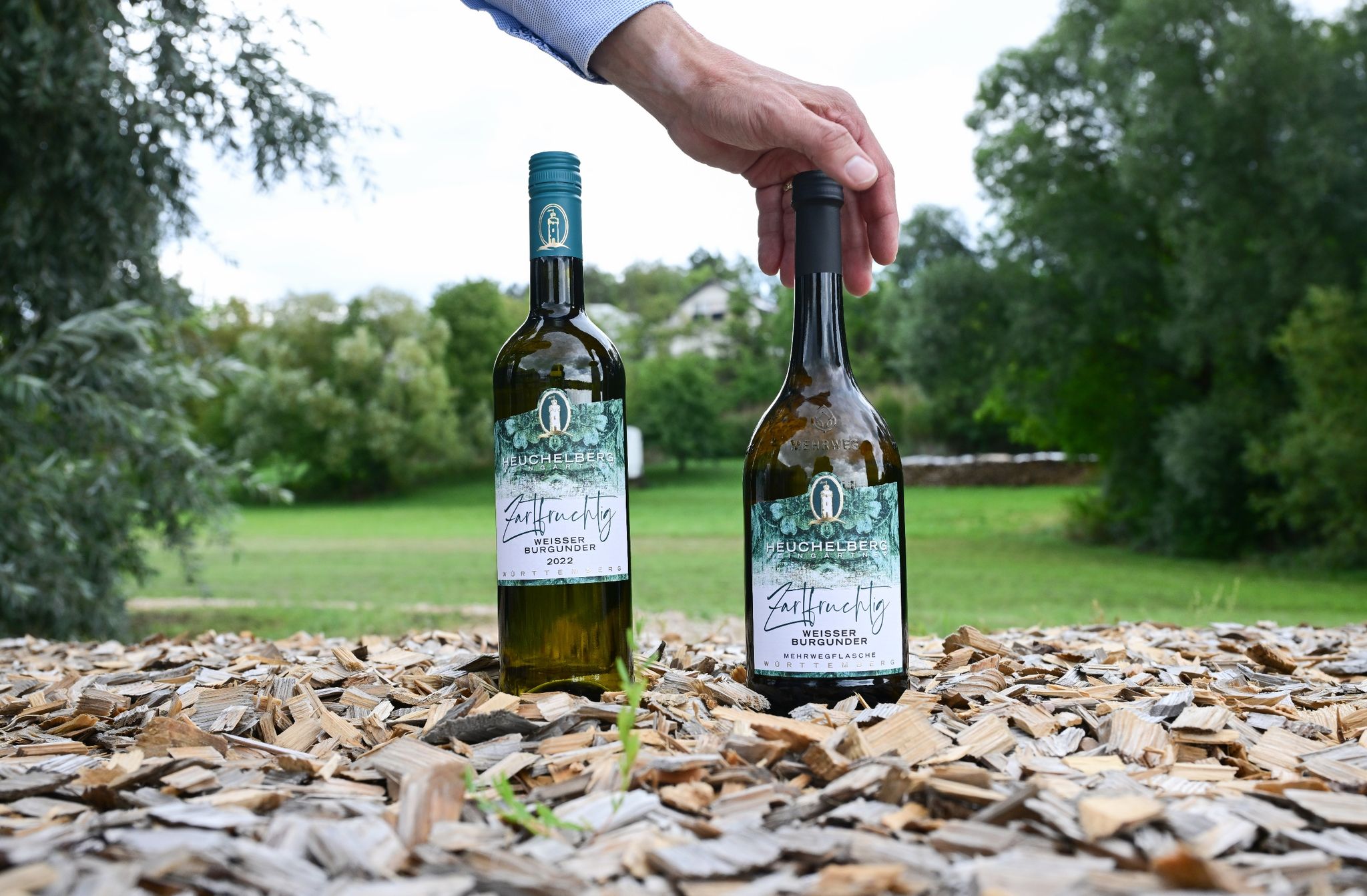 Eine 0,75 Liter Mehrweg Weinflasche (r) steht vor der Winzergenossenschaft Heuchelberger Weingärtner neben einer konventionellen Weinflasche (l).