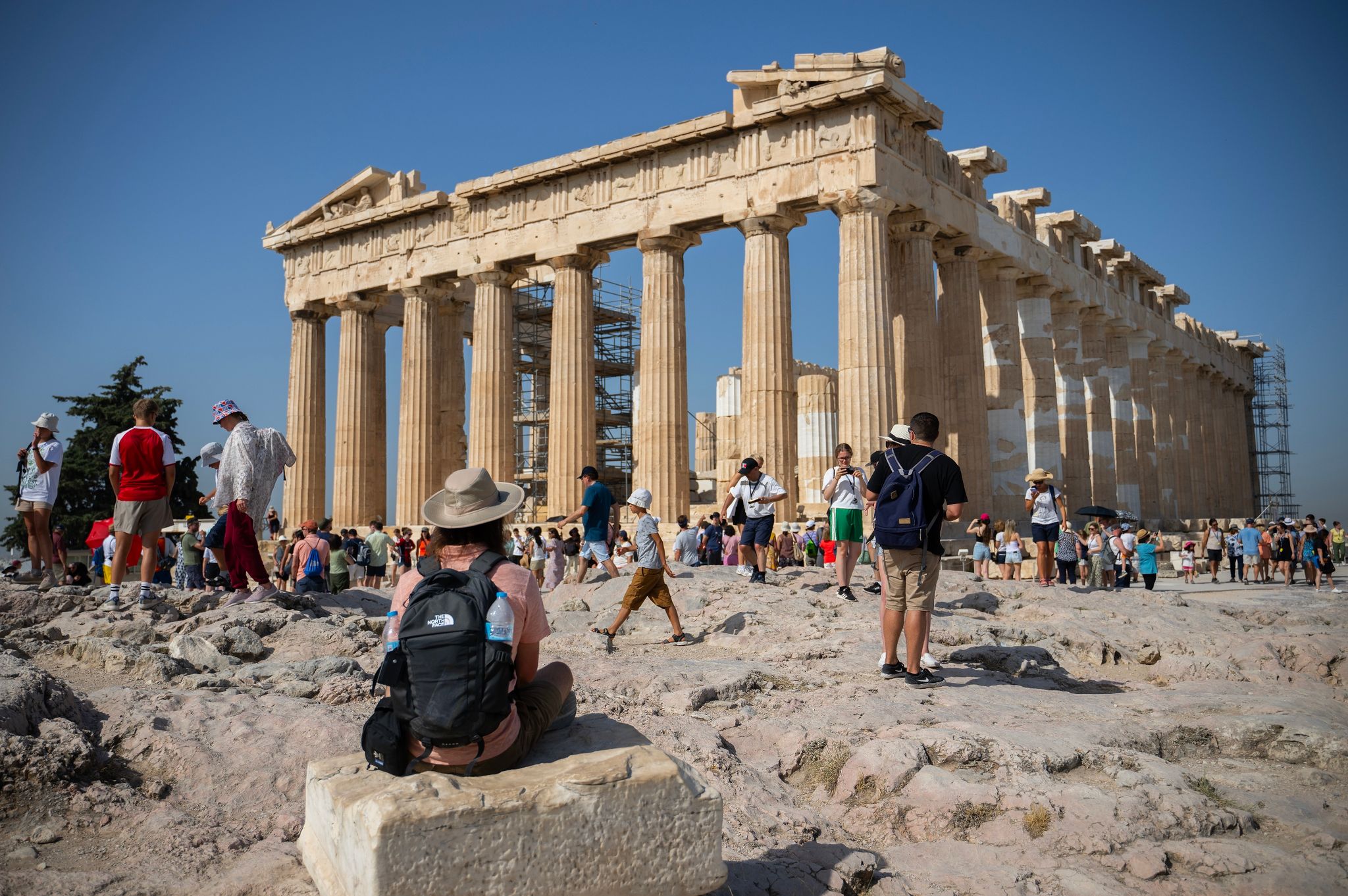 Touristen an einem heißen Tag bei ihrem Besuch des Parthenon-Tempels auf dem Akropolis-Hügel in Athen.