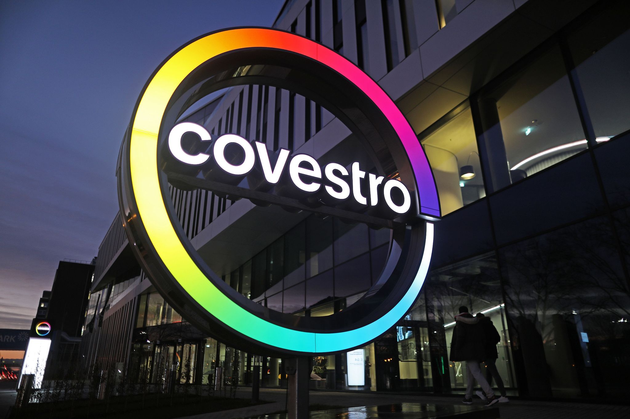 Das Logo des Chemiekonzerns Covestro leuchtet vor der Unternehmenszentrale.